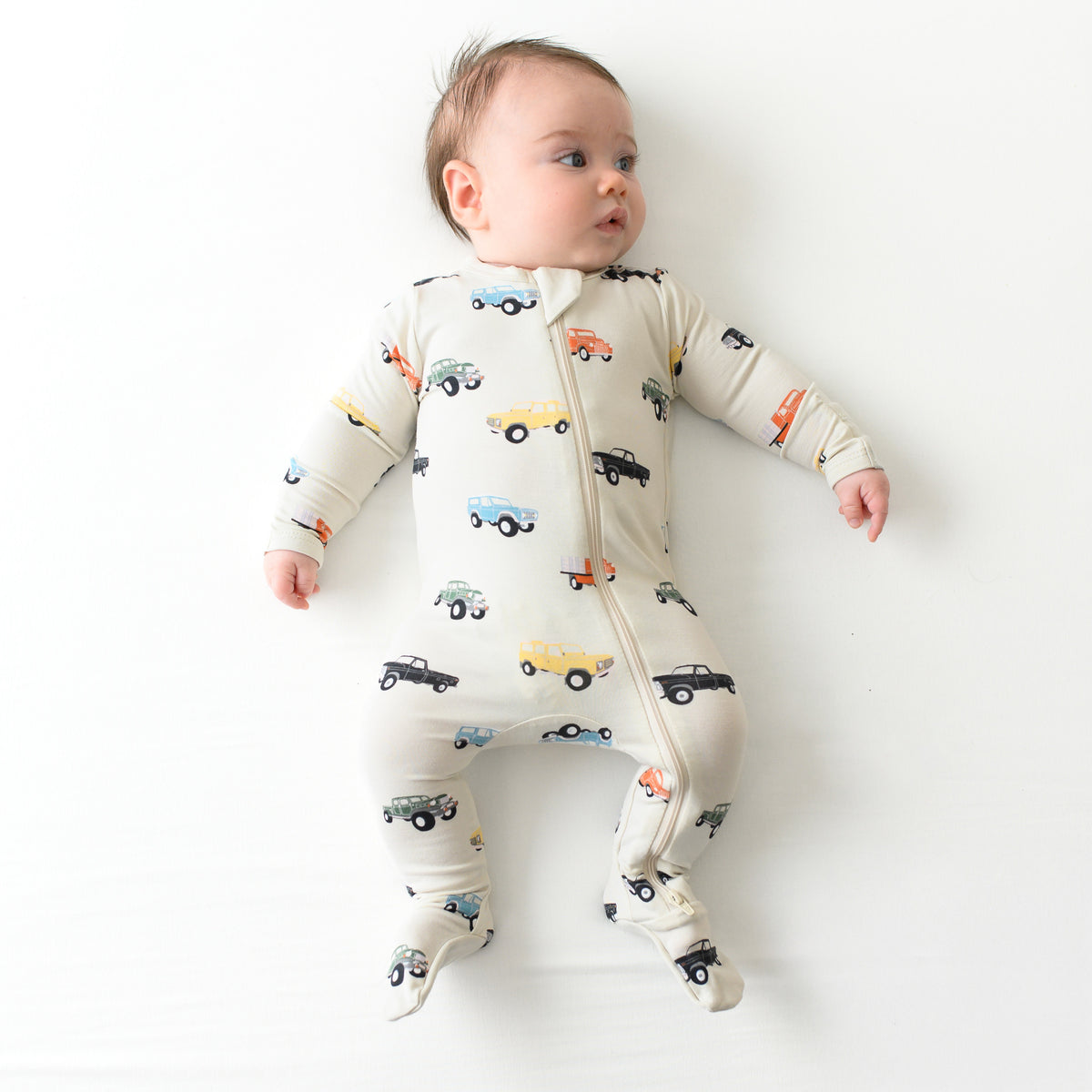 Infant wearing Zippered Footie bamboo pajamas in Vintage Truck