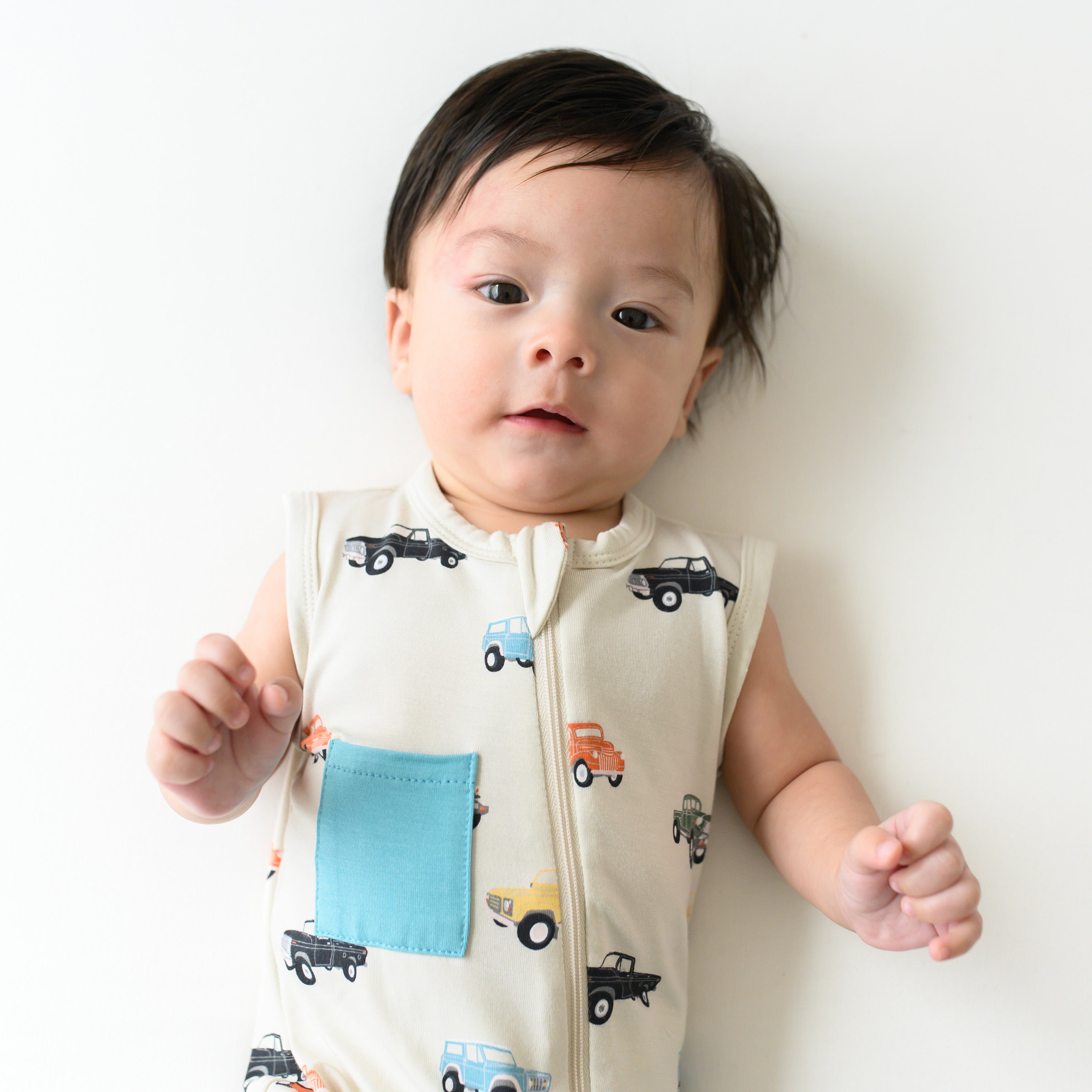 Infant wearing Kyte Baby Sleeveless Zippered Romper with Dual Zipper in Vintage Truck