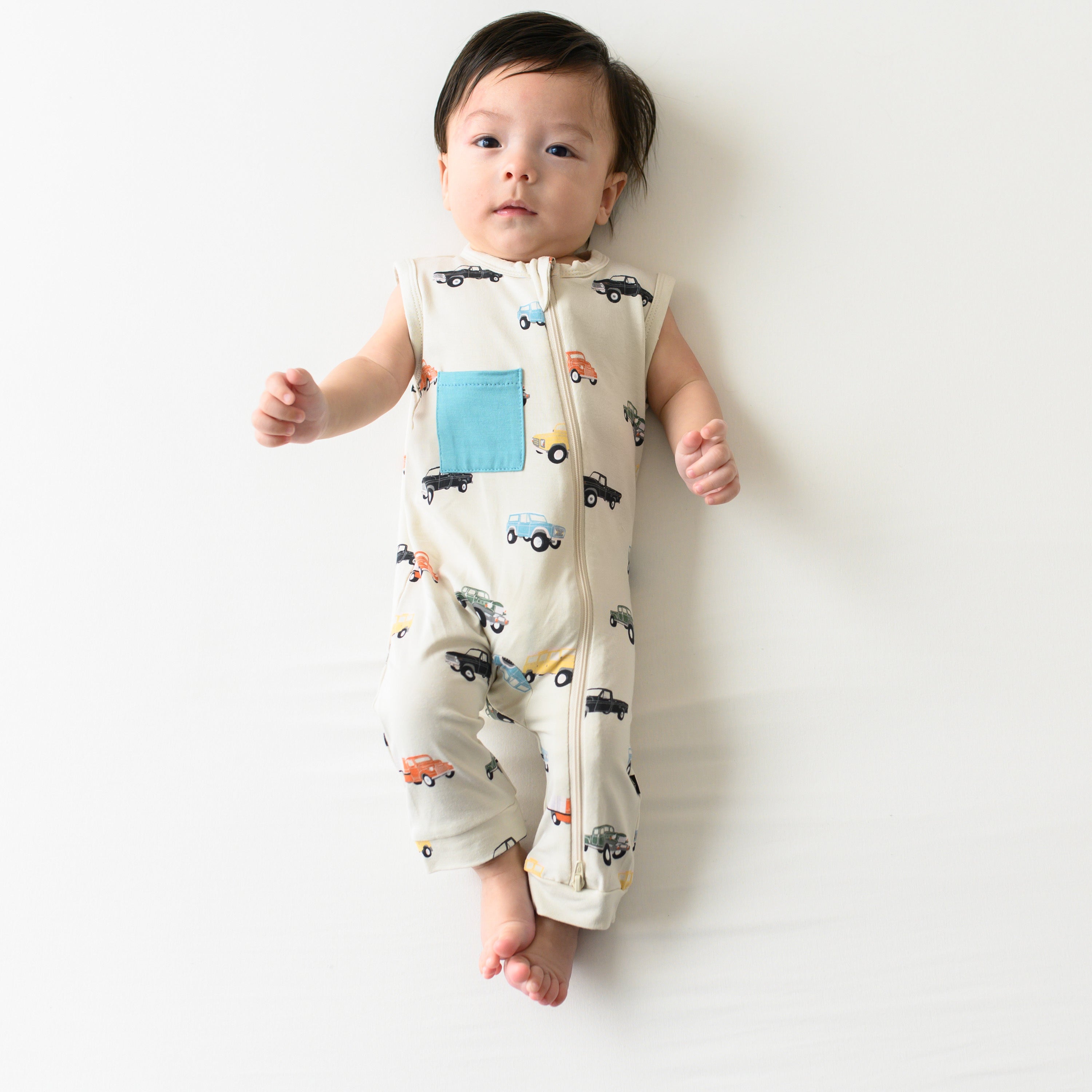 Infant wearing Kyte Baby Sleeveless Zippered Romper in Vintage Truck