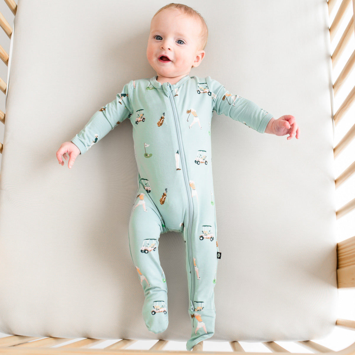 Baby modeling Zippered Footie in Golf print