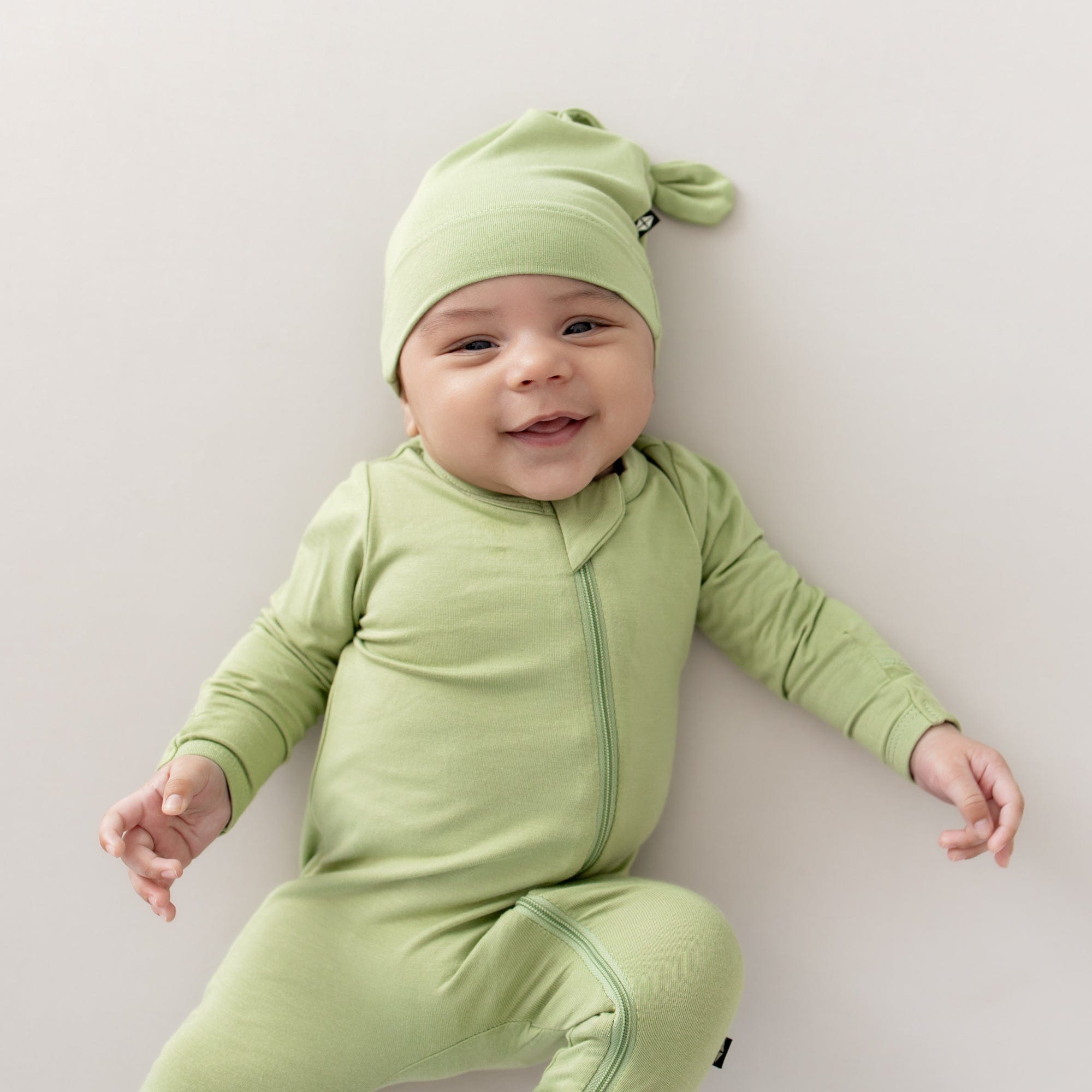 Baby wearing zippered footie and knotted cap hospital newborn outfit in Honu green