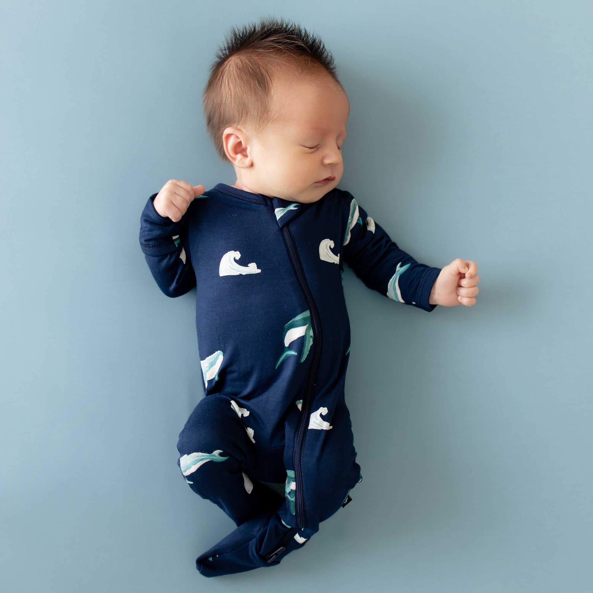 Baby sleeping in Zippered Footie in Humpback whale print