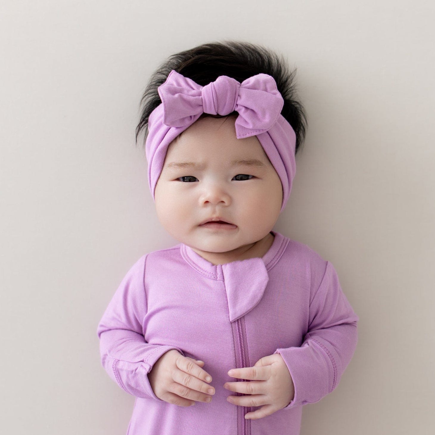 baby wearing zippered footie and bow in poi
