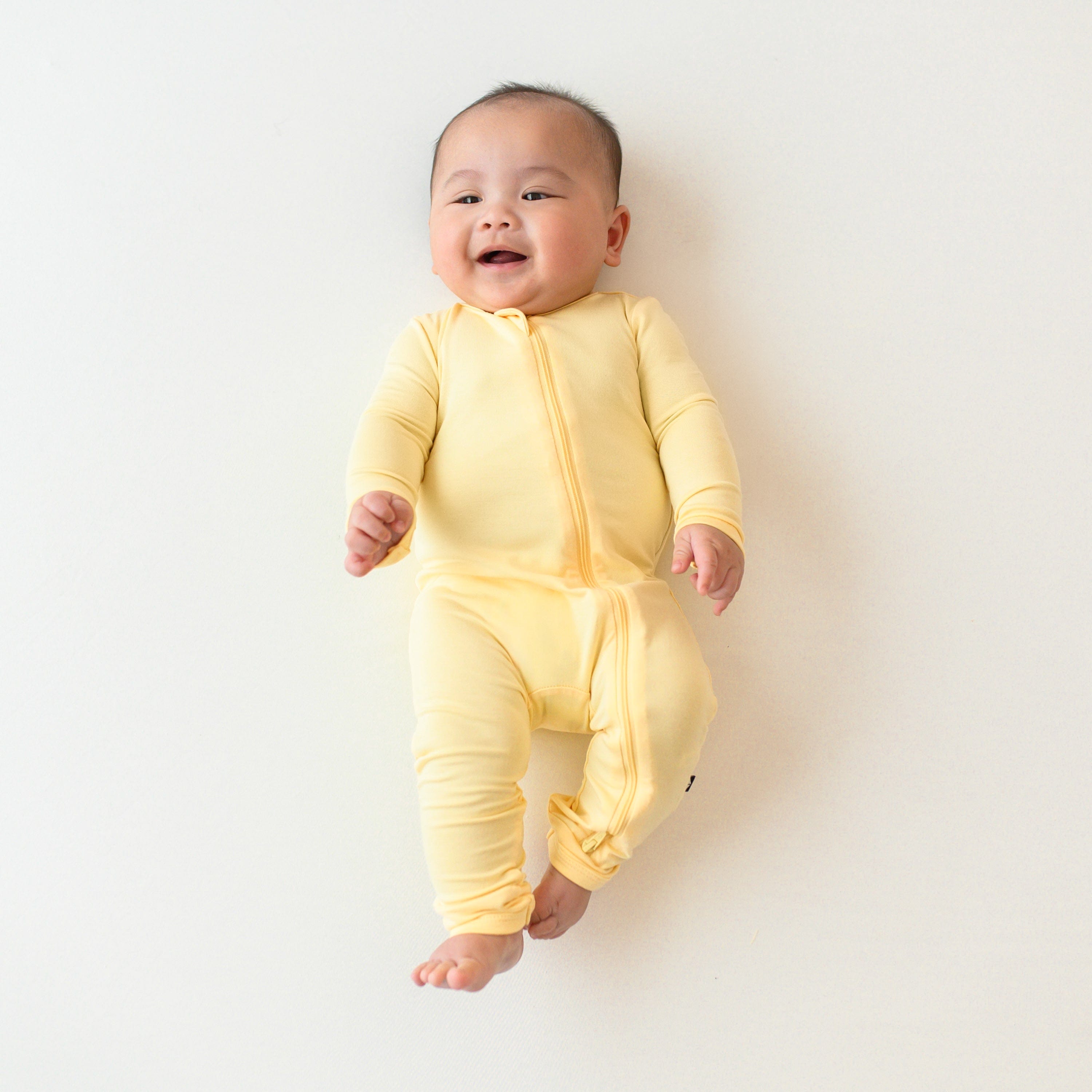 Smiling baby in zippered romper in lilikoi