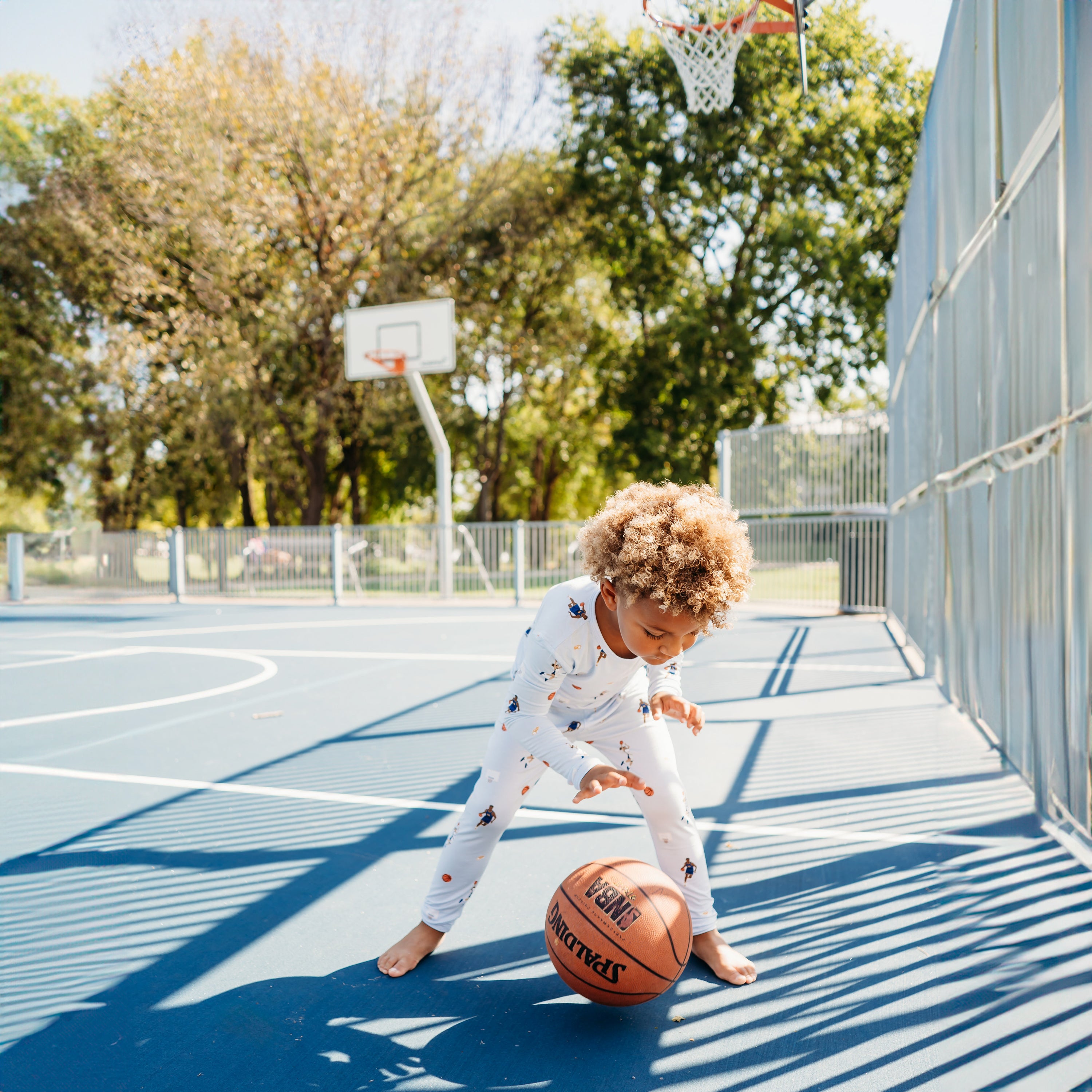 A boy wearing the Long Sleeve Pajamas in Basketball dribbling a basketball on a basketball court