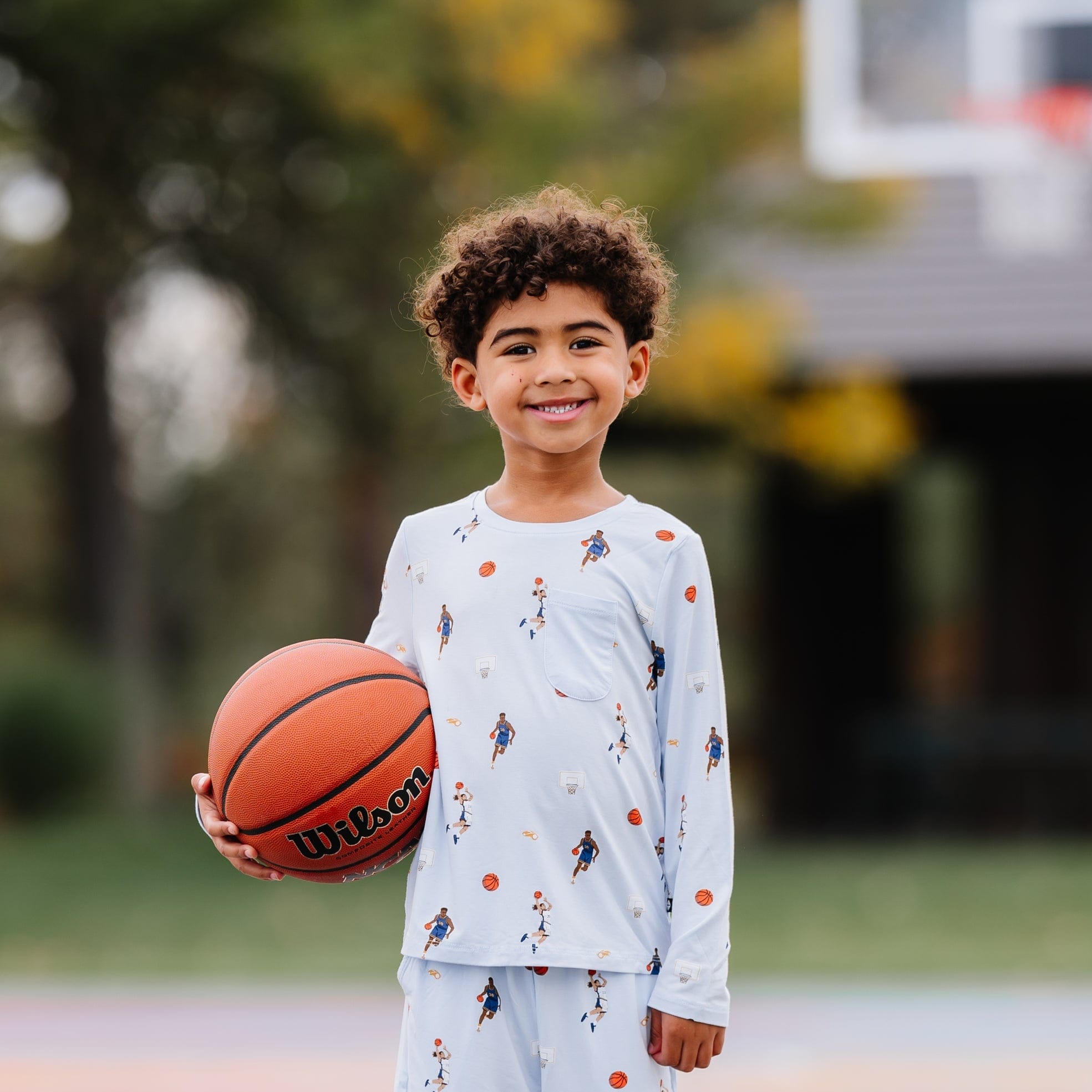 Young boy holding a basketball wearing the Long Sleeve Toddler Crew Neck Tee in Basketball