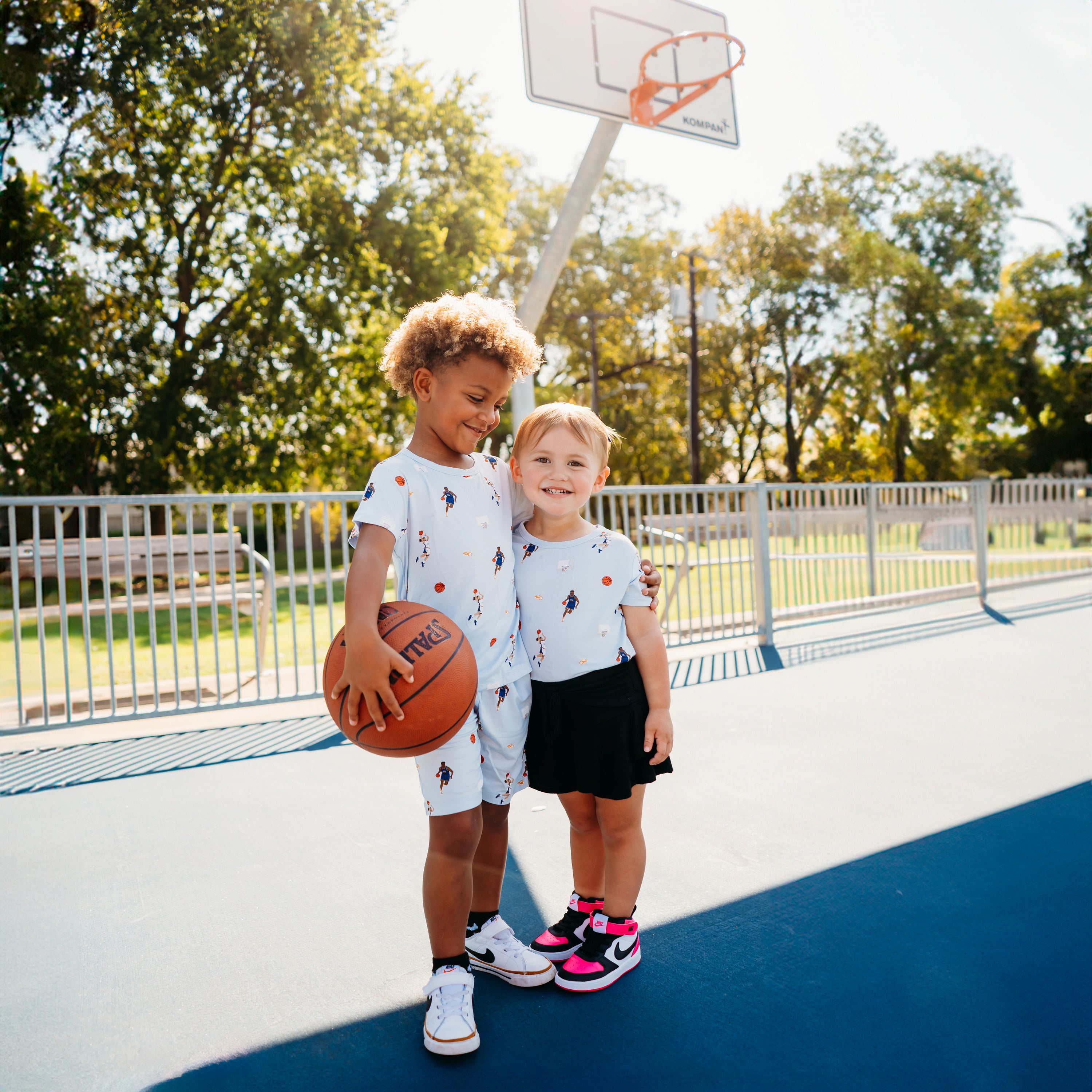 Young boy and girl standing beside one another on a basketball court wearing various items from the Basketball collection
