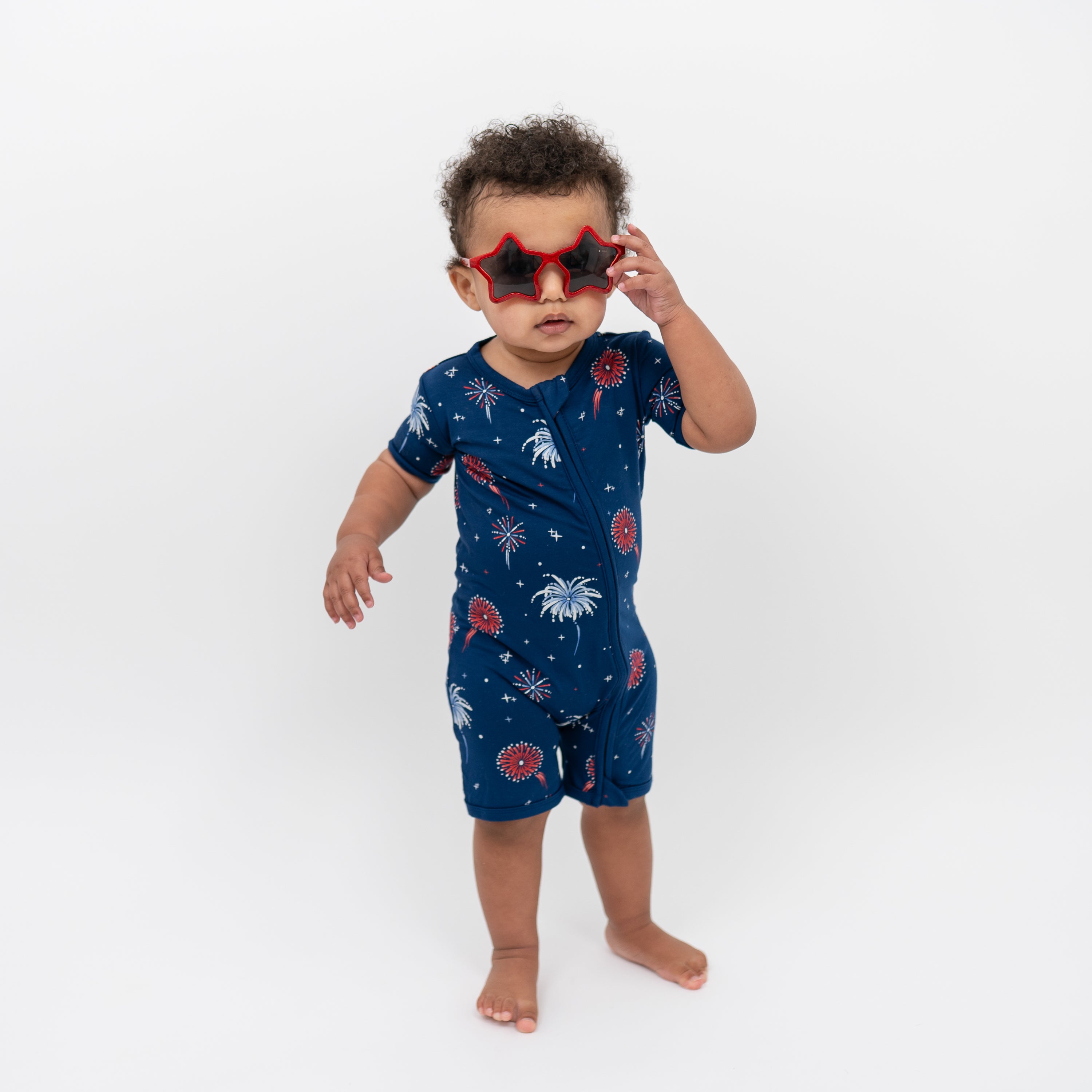 Toddler modeling Zippered Shortall Romper in Celebration wearing star sunglasses