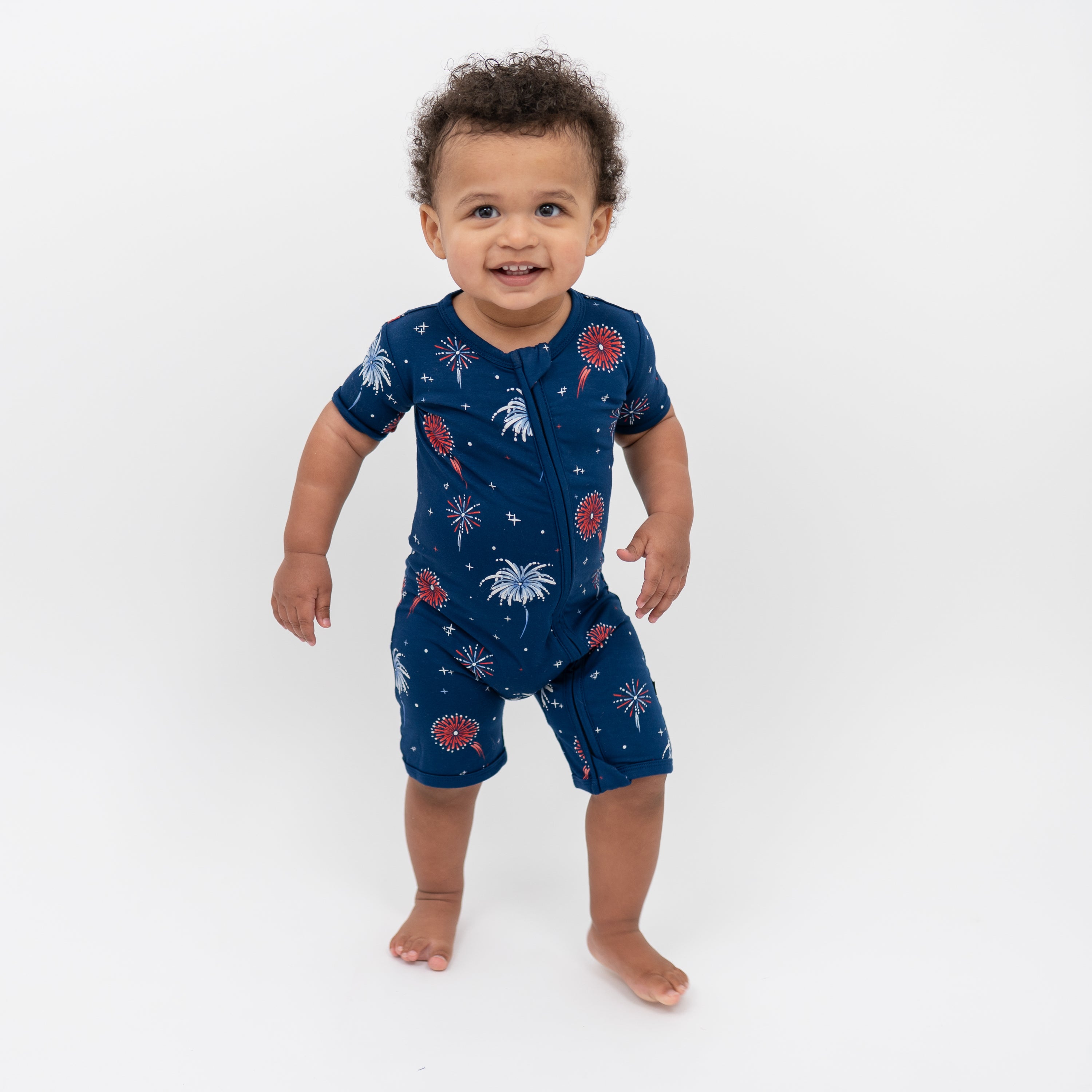 Toddler smiling wearing Zippered Shortall Romper in Celebration