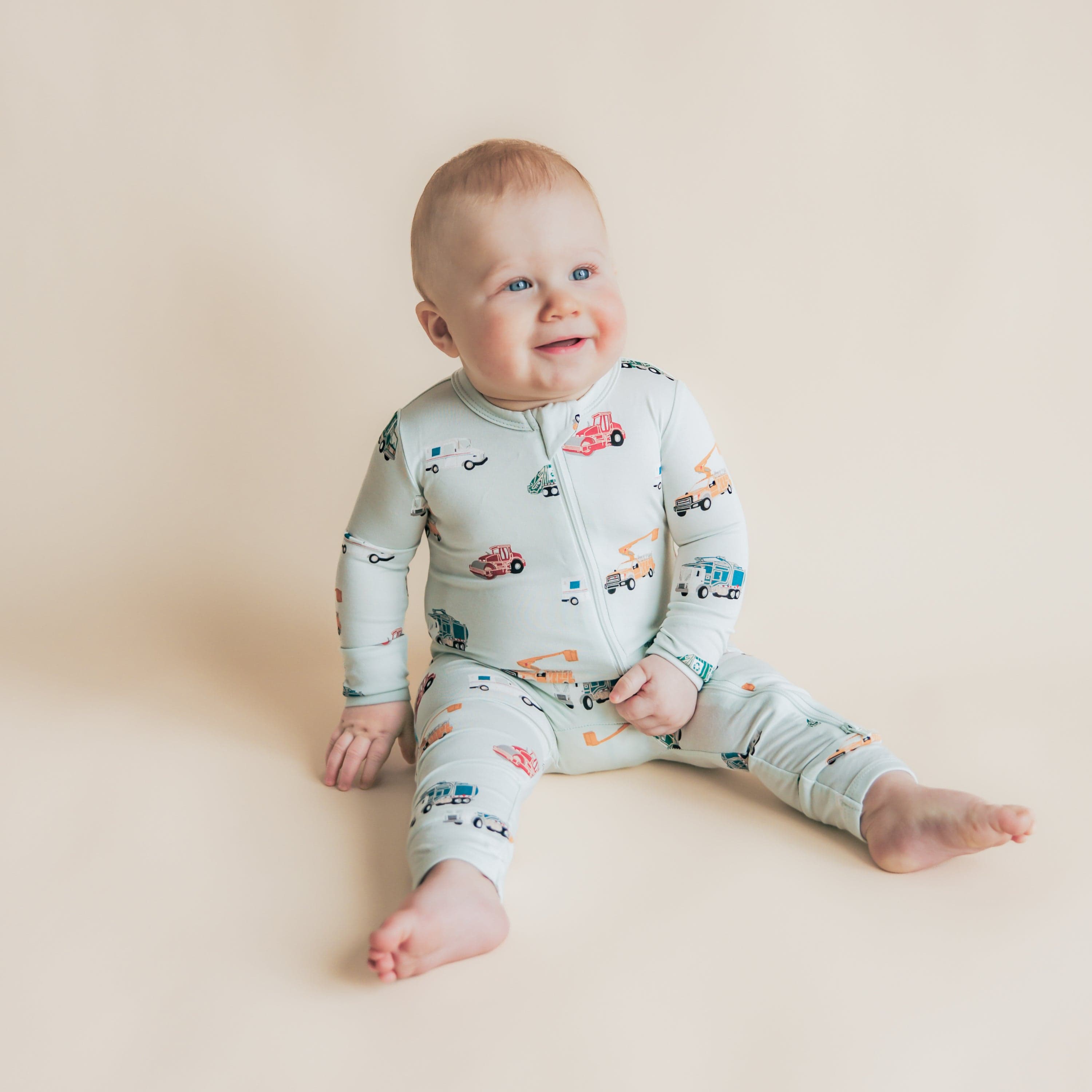 Toddler sitting on the floor wearing the soft and stretchy Zippered Romper in City Vehicles