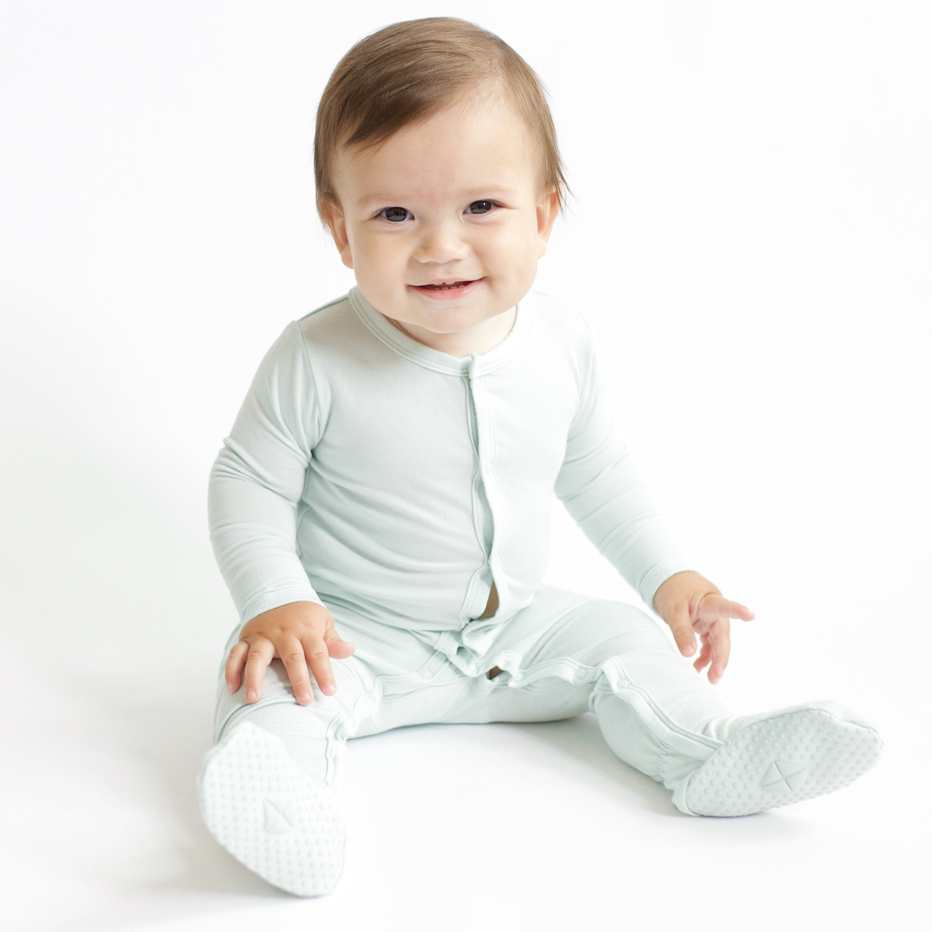 Infant sitting wearing the Footie in Dew