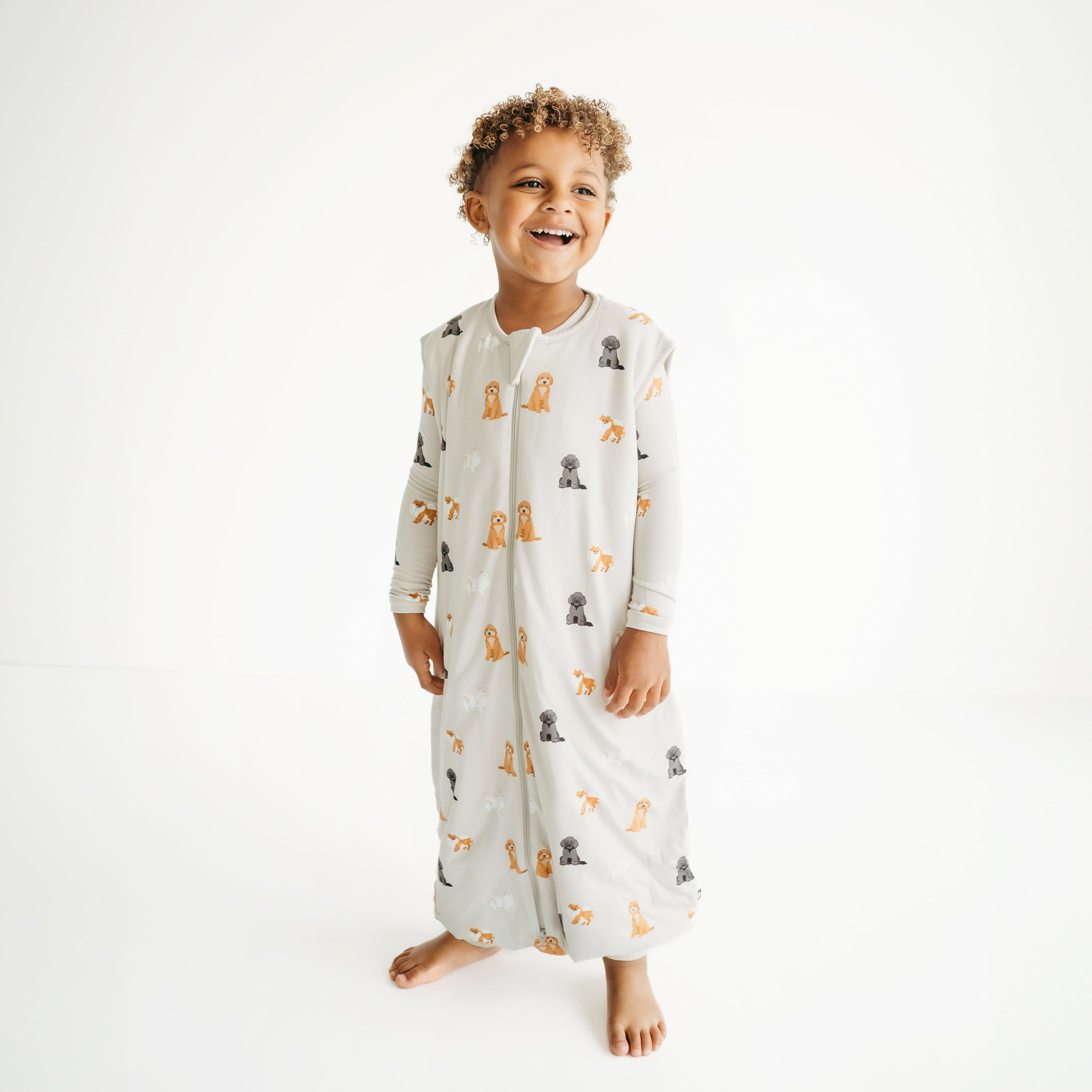 Boy modeling Sleep Bag Walker in Fluffy Dog 1.0 with matching Fluffy Dog pajamas underneath