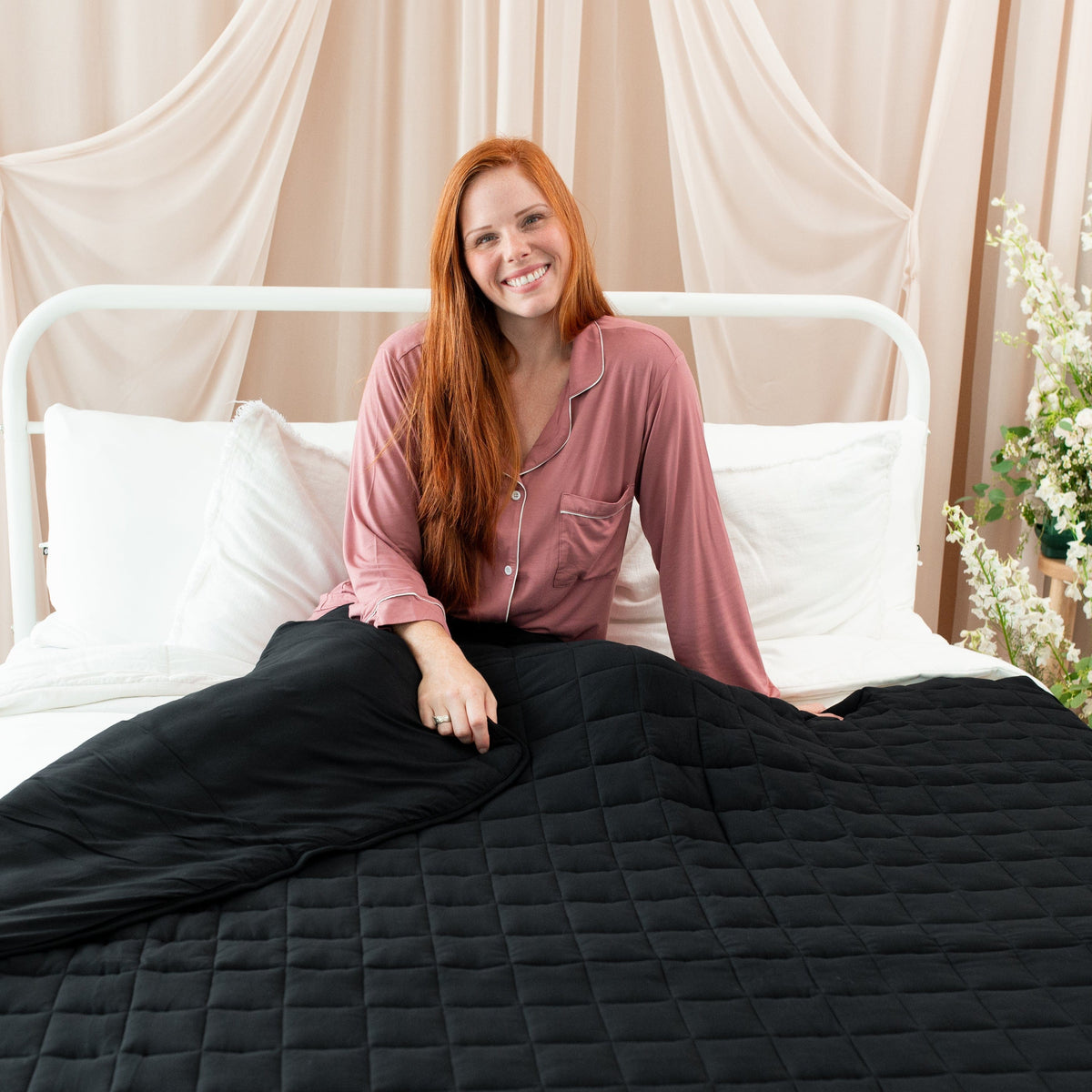 Woman using Kyte Baby 3.5 TOG Adult Quilted Blanket in Midnight black