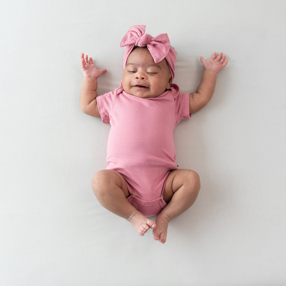 Newborn wearing Pink Onesie and Knotted Bow Headband in Apple Blossom