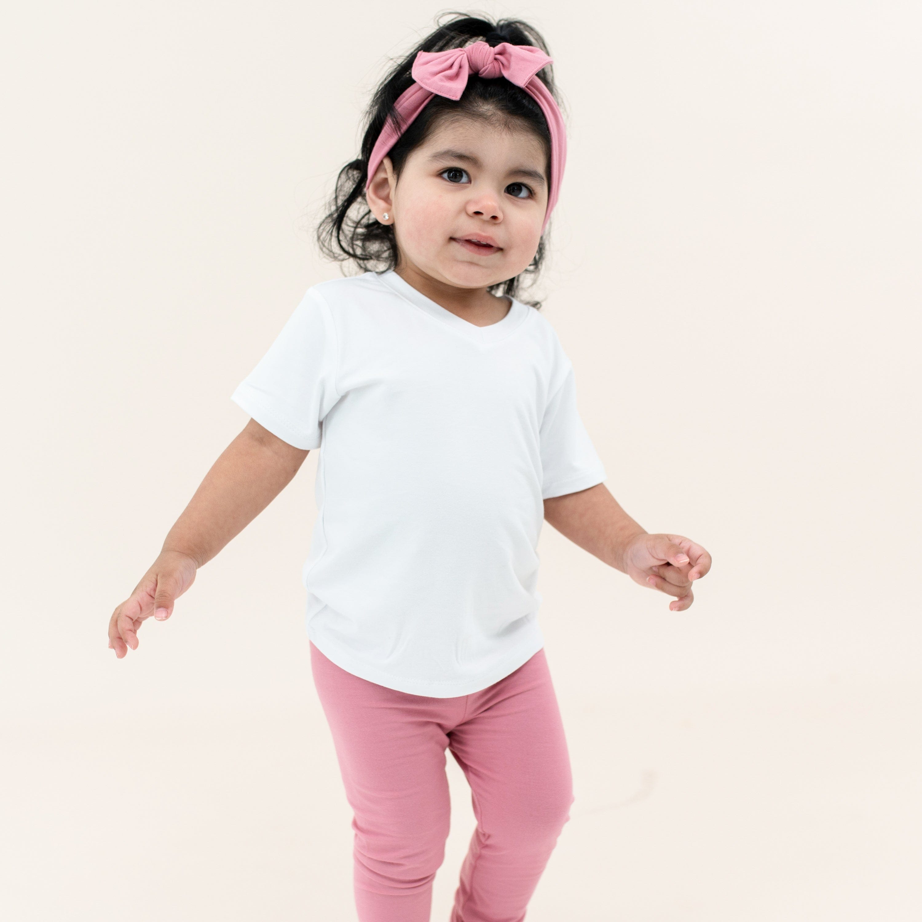 Toddler wearing White t-shirt with pink leggings and Apple Blossom knotted bow headband