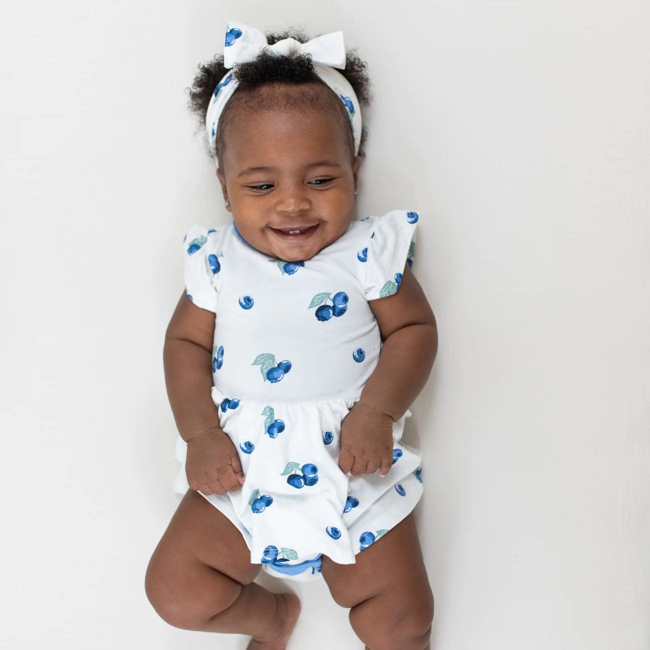 Girl wearing Kyte Baby Bow headband in Blueberry pattern with matching dress