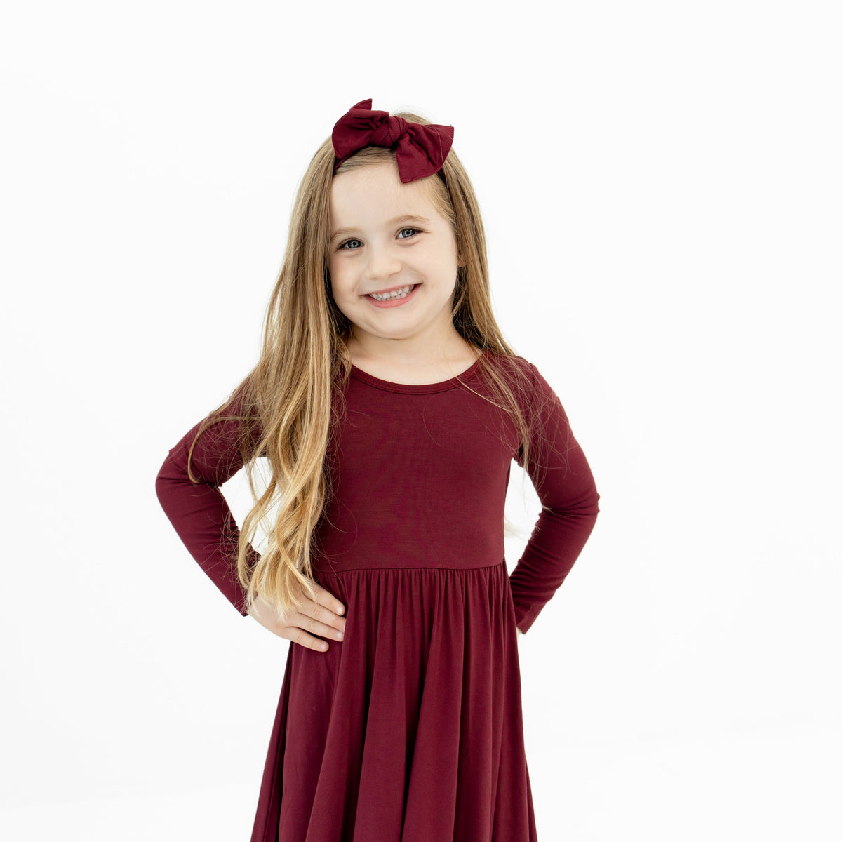 Girl wearing Knotted Bow Headband in Burgundy paired with matching twirl dress