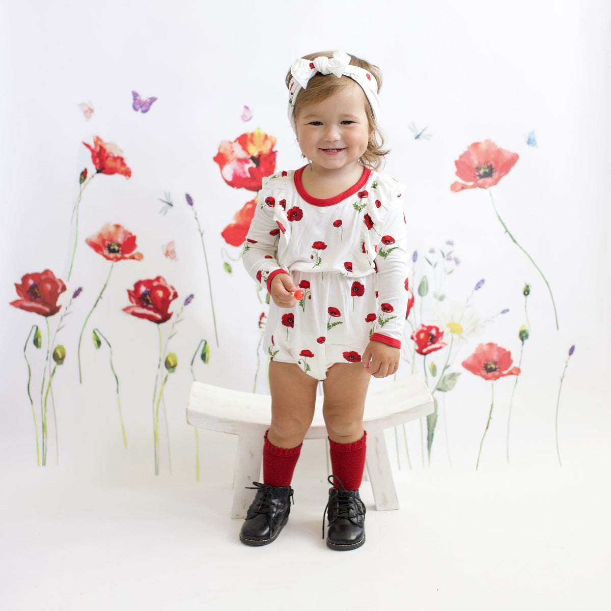 Toddler wearing Kyte Baby bamboo bow headband in Cloud Poppies