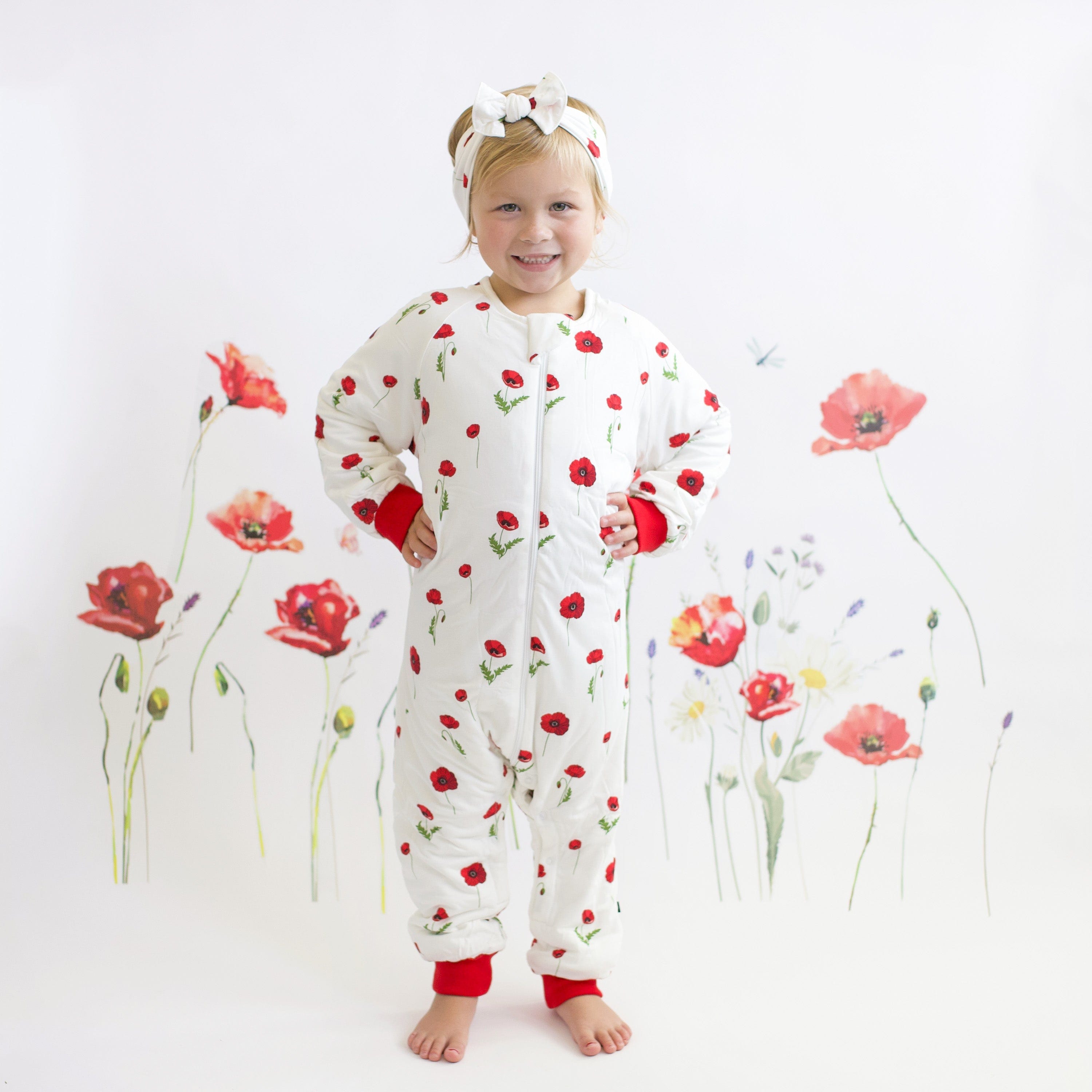 Toddler wearing Kyte Baby bamboo bow headband in Cloud Poppies with matching Sleep Bag Walker