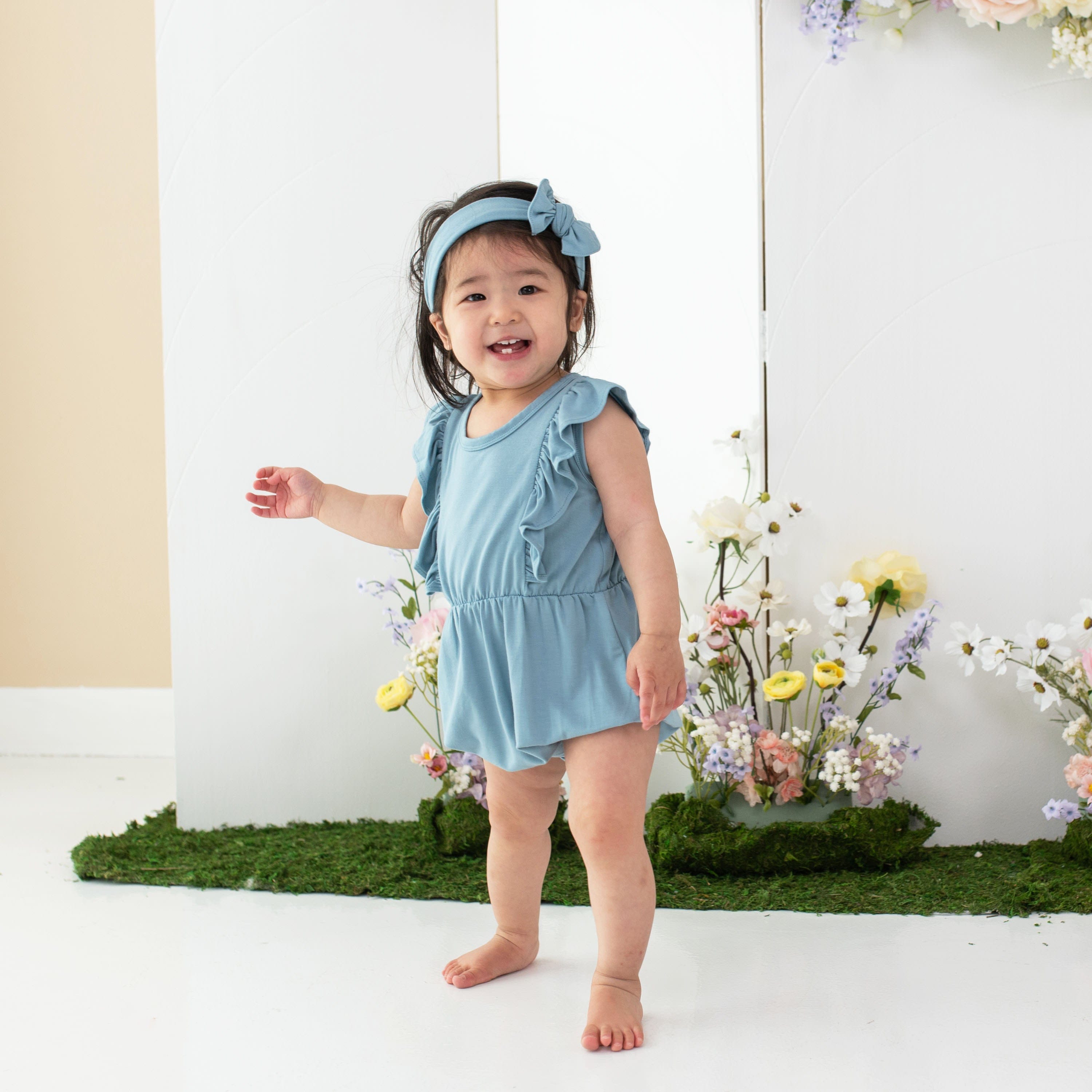 Toddler wearing Kyte Baby bamboo bow headband in Dusty Blue