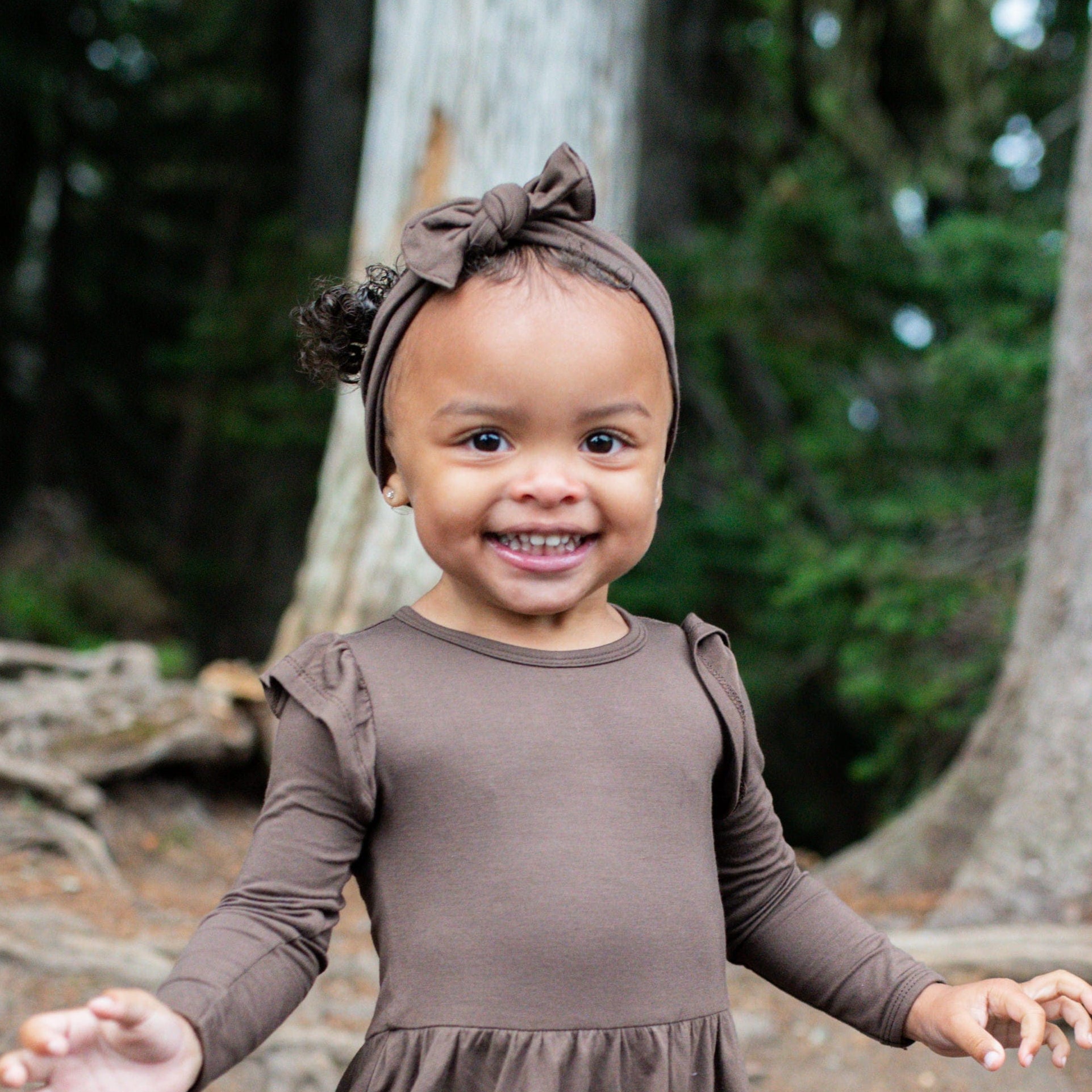 Toddler girls wearing the Knotted Bow Headband in Espresso paired with a twirl bodysuit dress