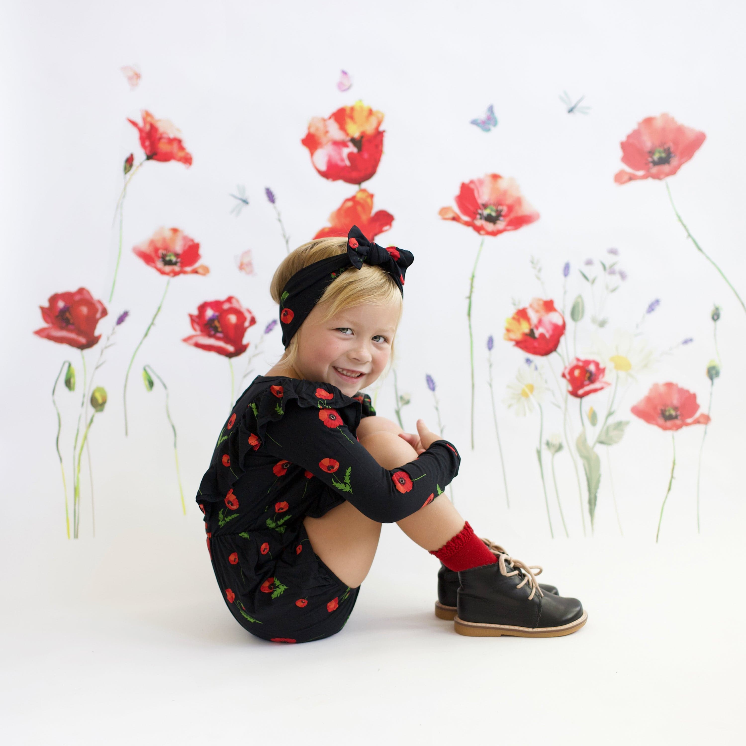 Girl wearing Kyte Baby Bow headband in Midnight Poppies