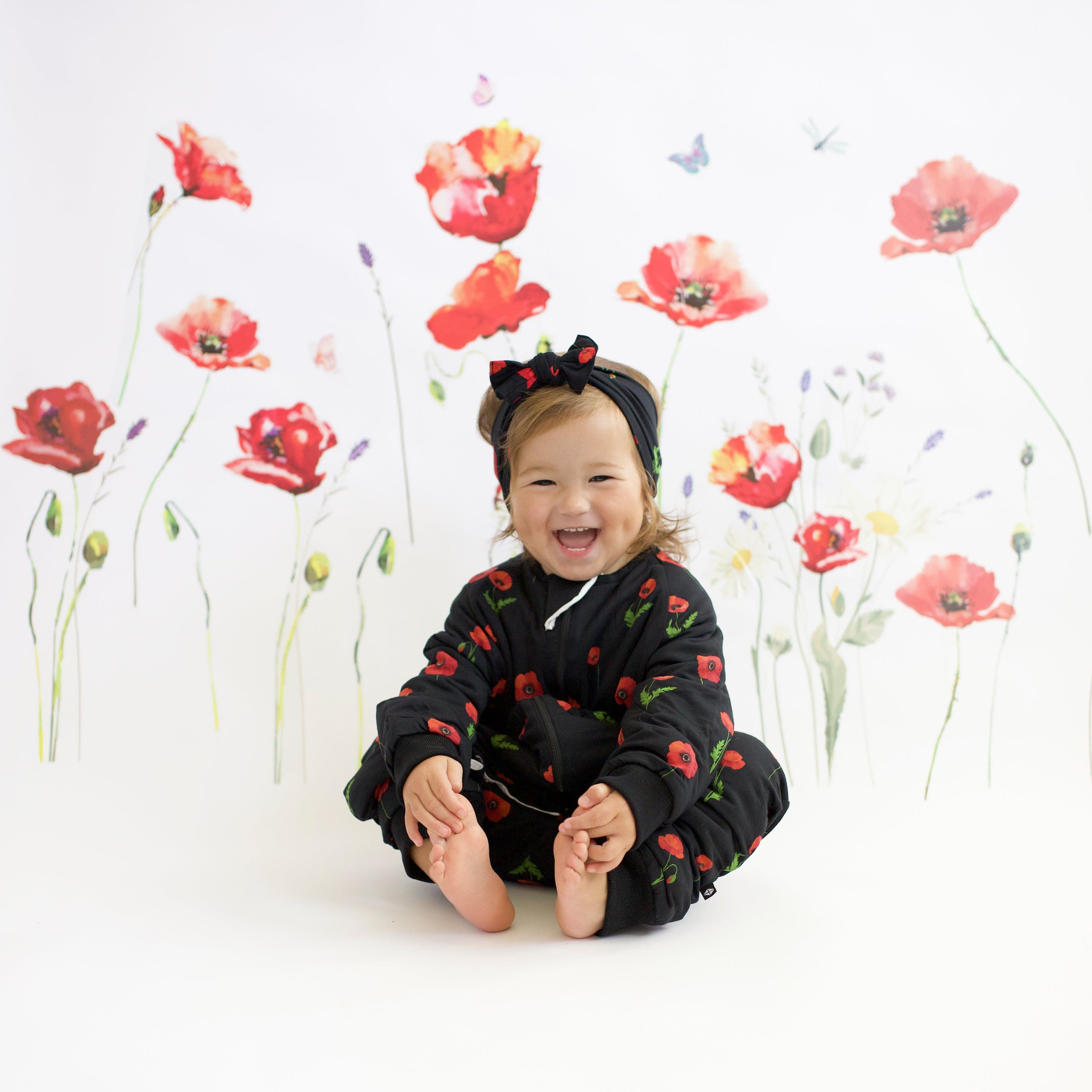 Toddler wearing Kyte Baby bamboo bow headband in Midnight Poppies