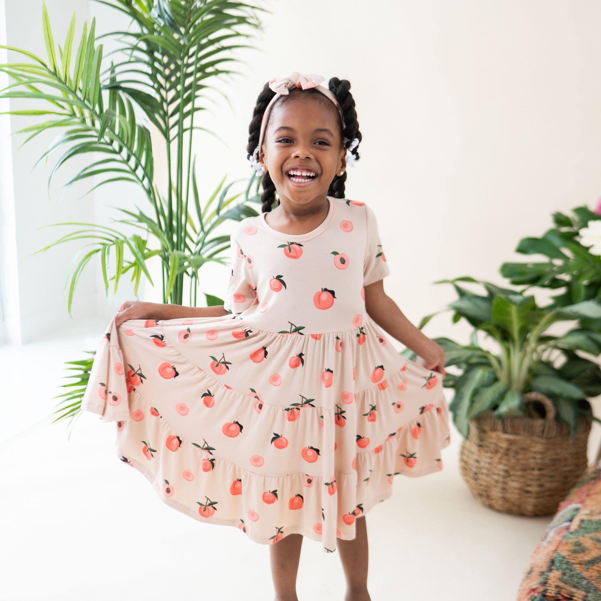 Child wearing Kyte Baby bamboo bow headband in Peach