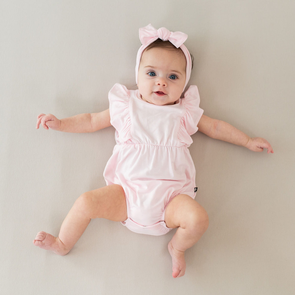 Infant wearing Kyte Baby Bow in Sakura Pink