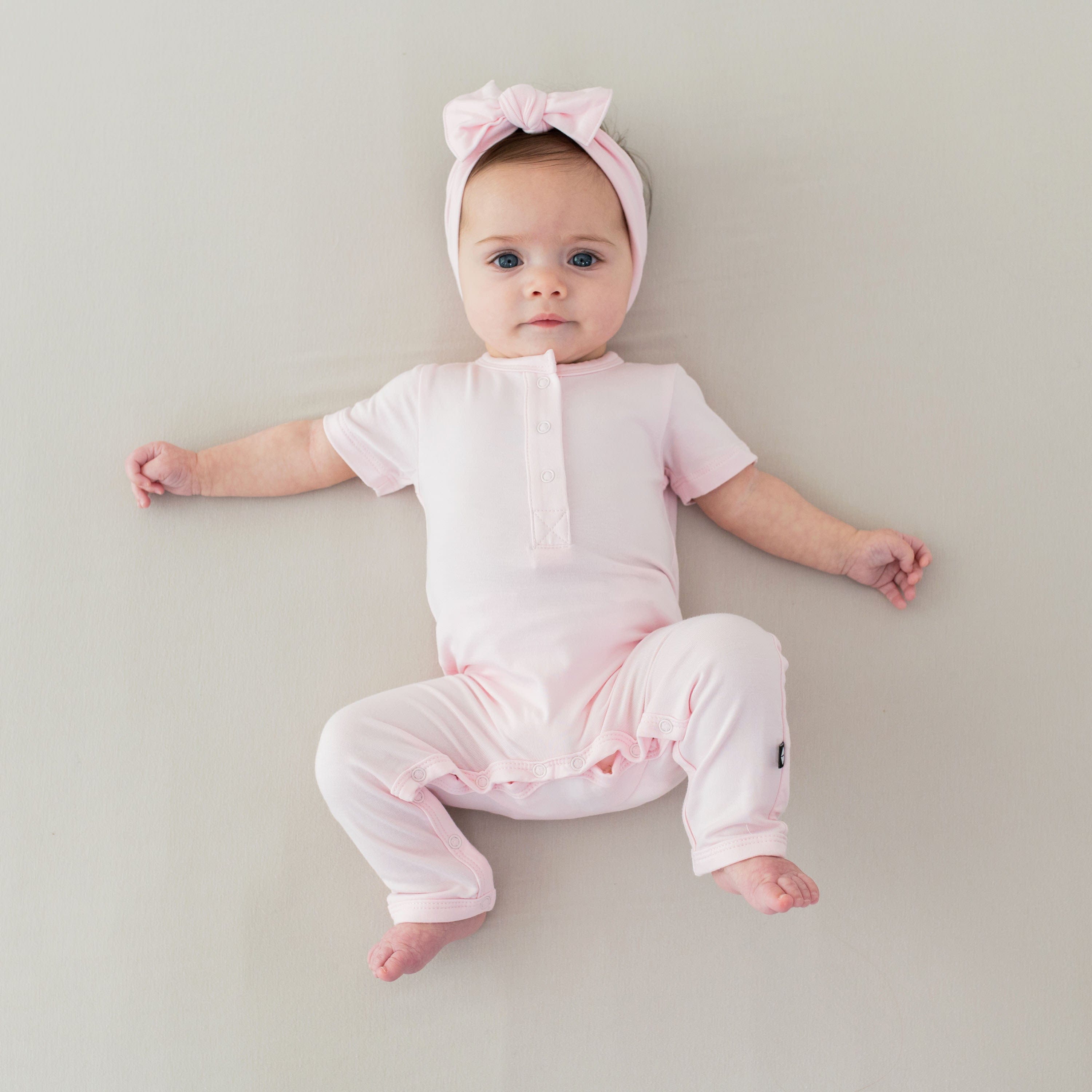 Infant wearing Kyte Baby Bow Headband in Sakura