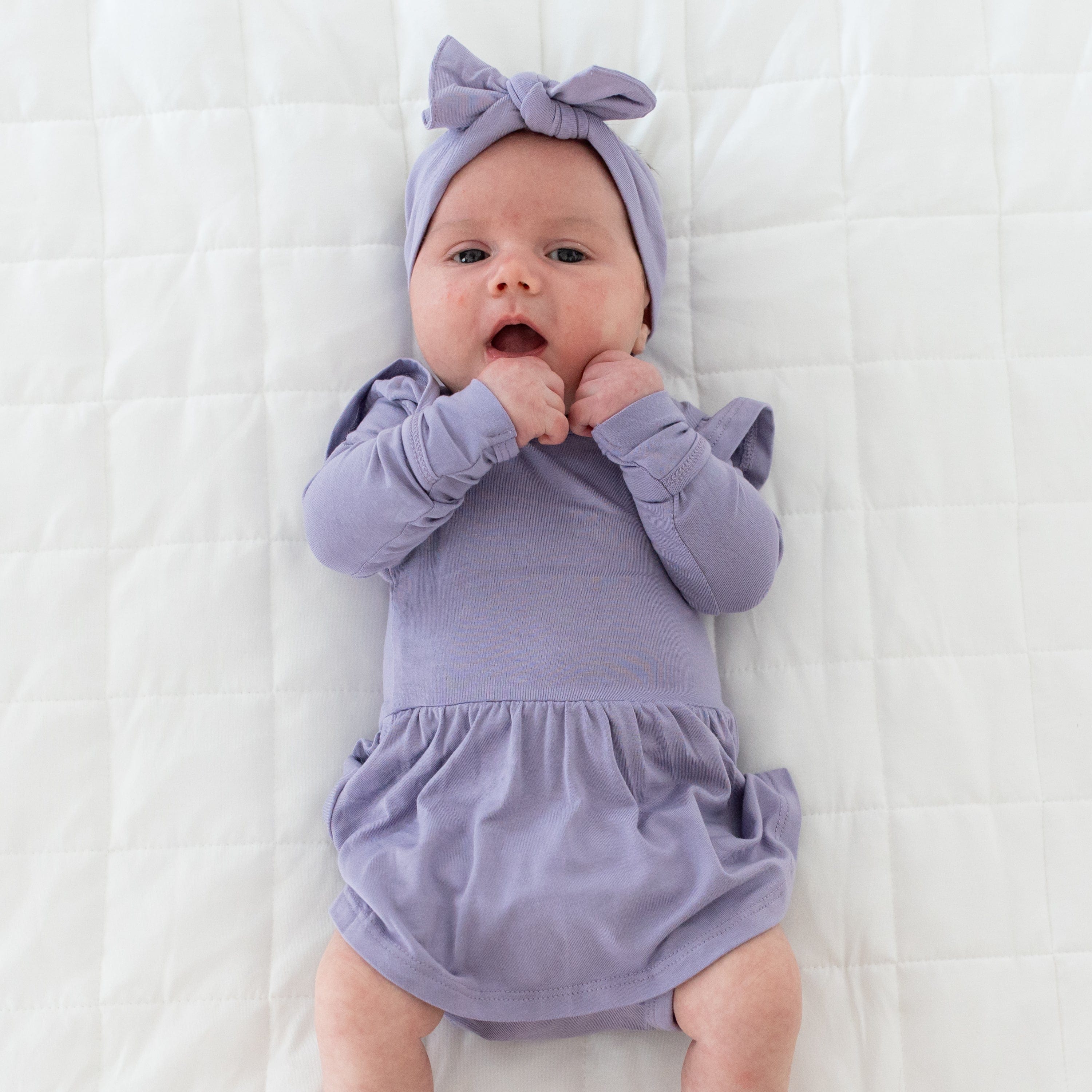 Newborn wearing Kyte Baby Bow headband in Taro and matching Long Sleeve Twirl Bodysuit