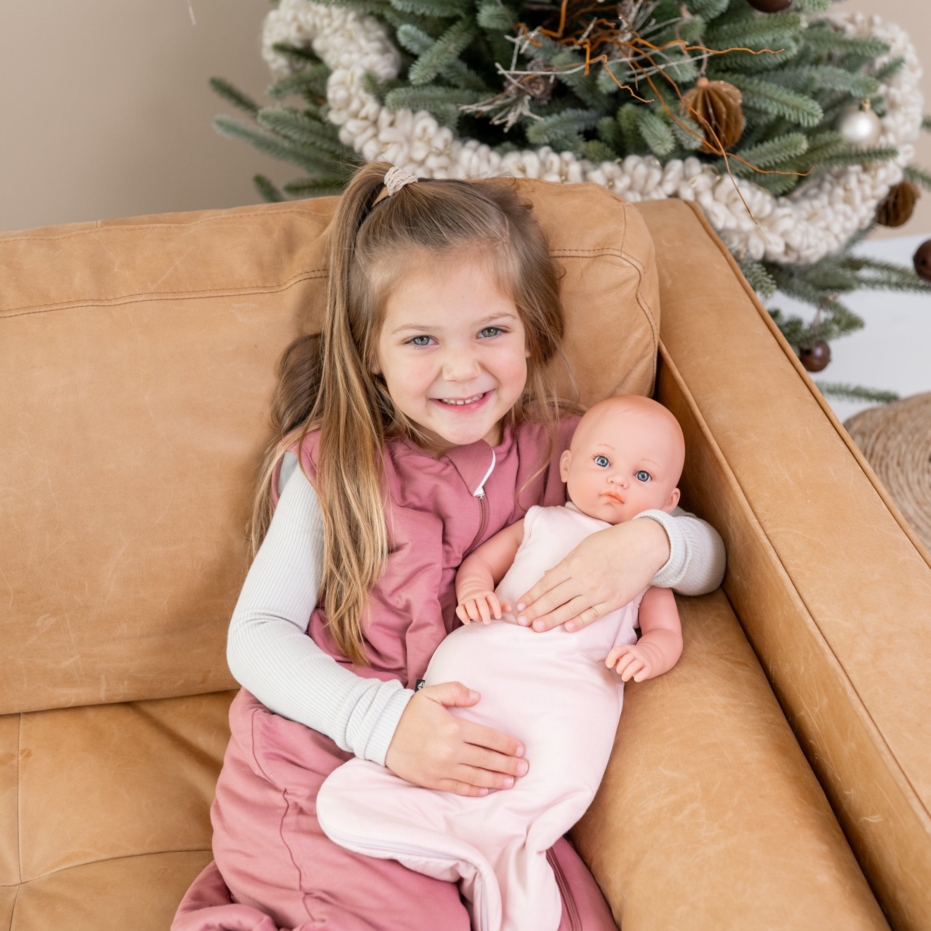 Child Holding Doll in Kyte Baby Doll Sleep Bag in Blush pink