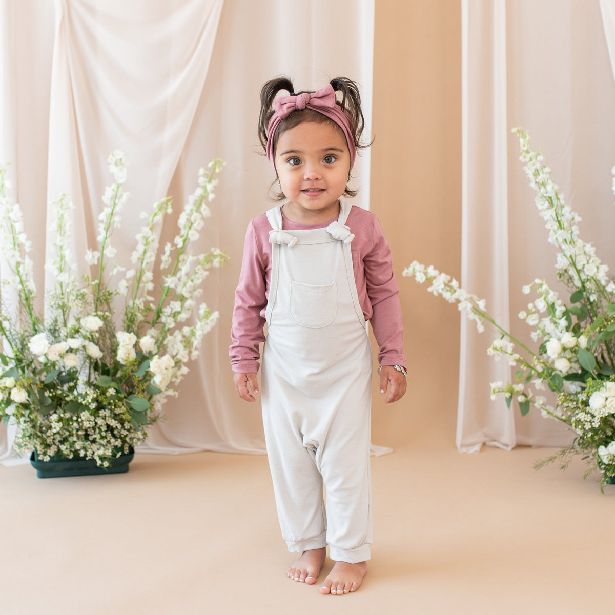 Girl wearing Kyte Baby Bamboo Jersey Overall in Oat