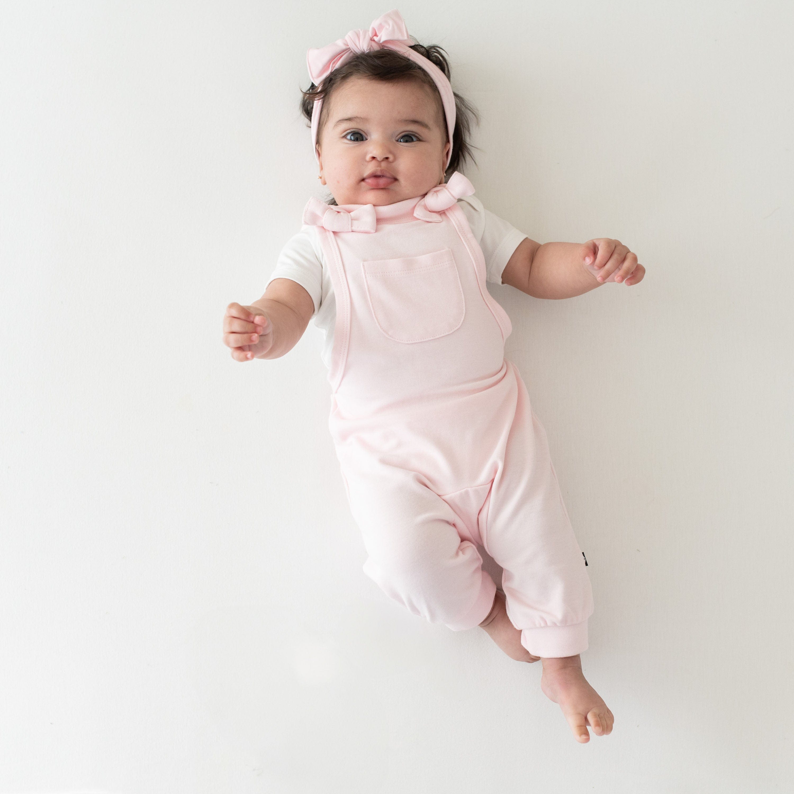 Infant wearing Kyte Baby Bamboo Jersey Overall in Sakura