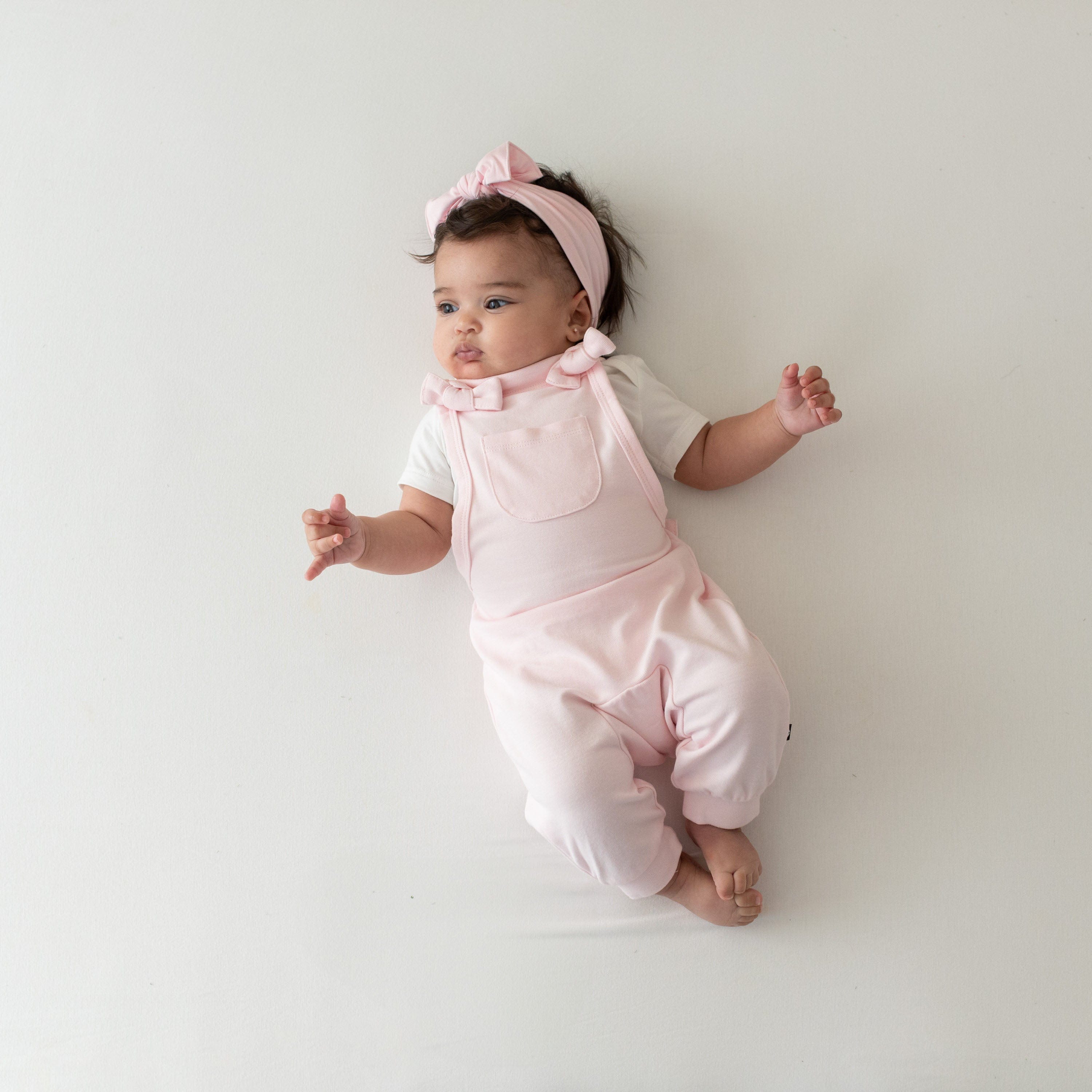 Infant wearing Kyte Baby Bamboo Jersey adjustable Overall in Sakura pink