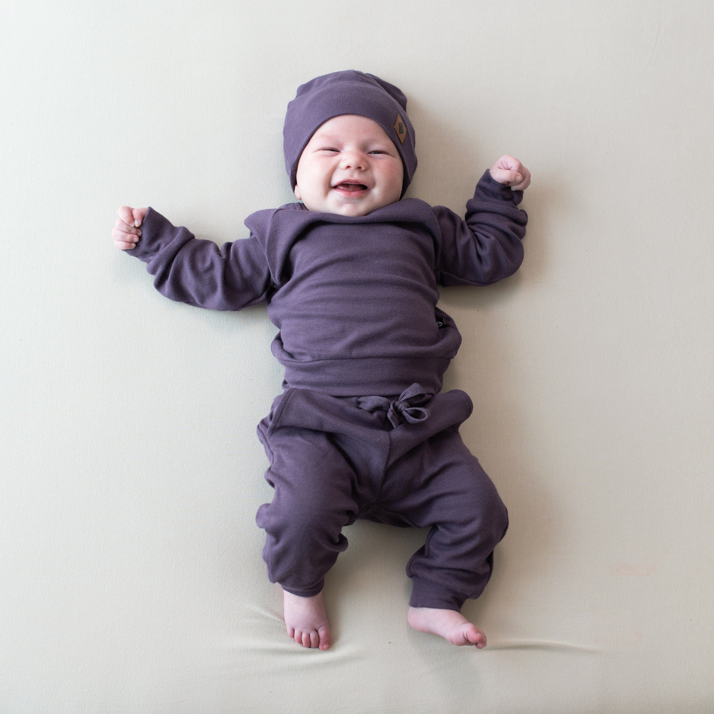 Baby wearing Bamboo Jersey Jogger Set and matching beanie in Currant