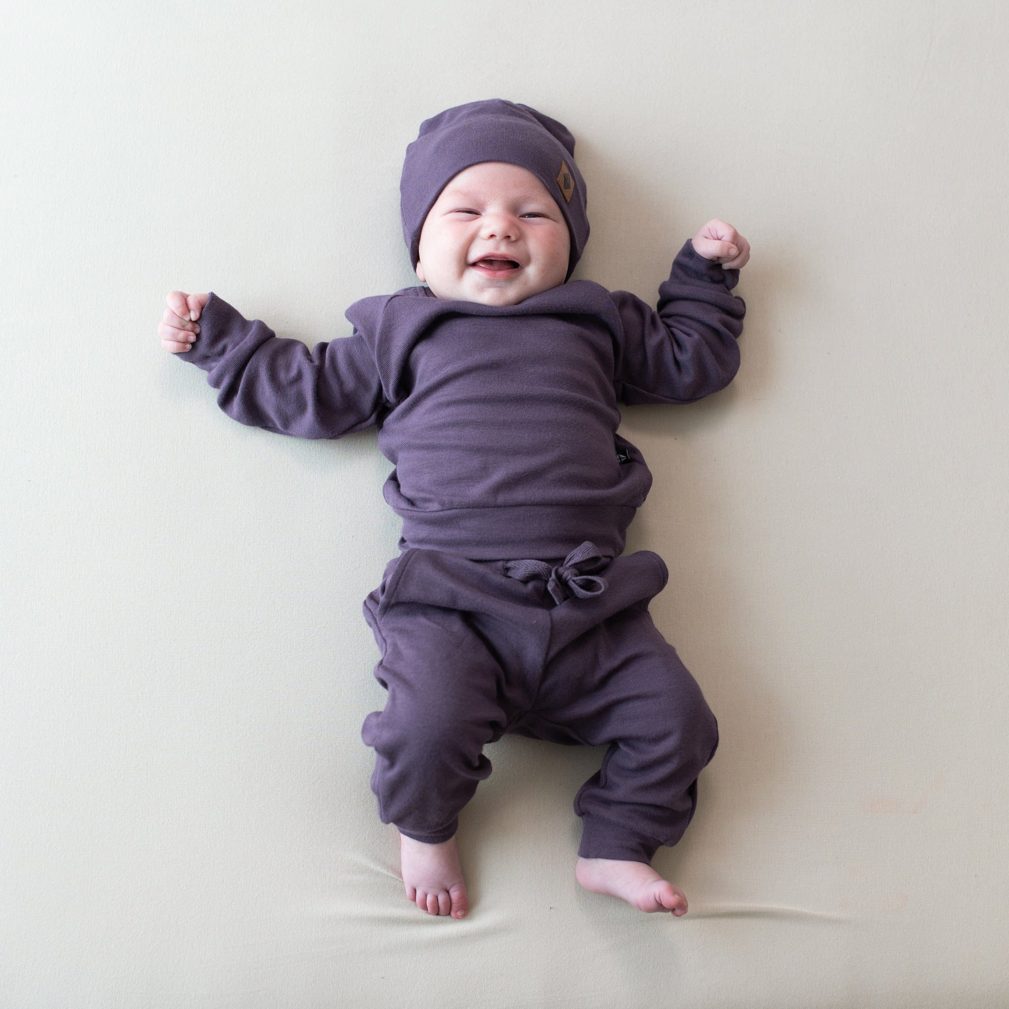 Baby wearing Bamboo Jersey Jogger Set and matching beanie in Currant