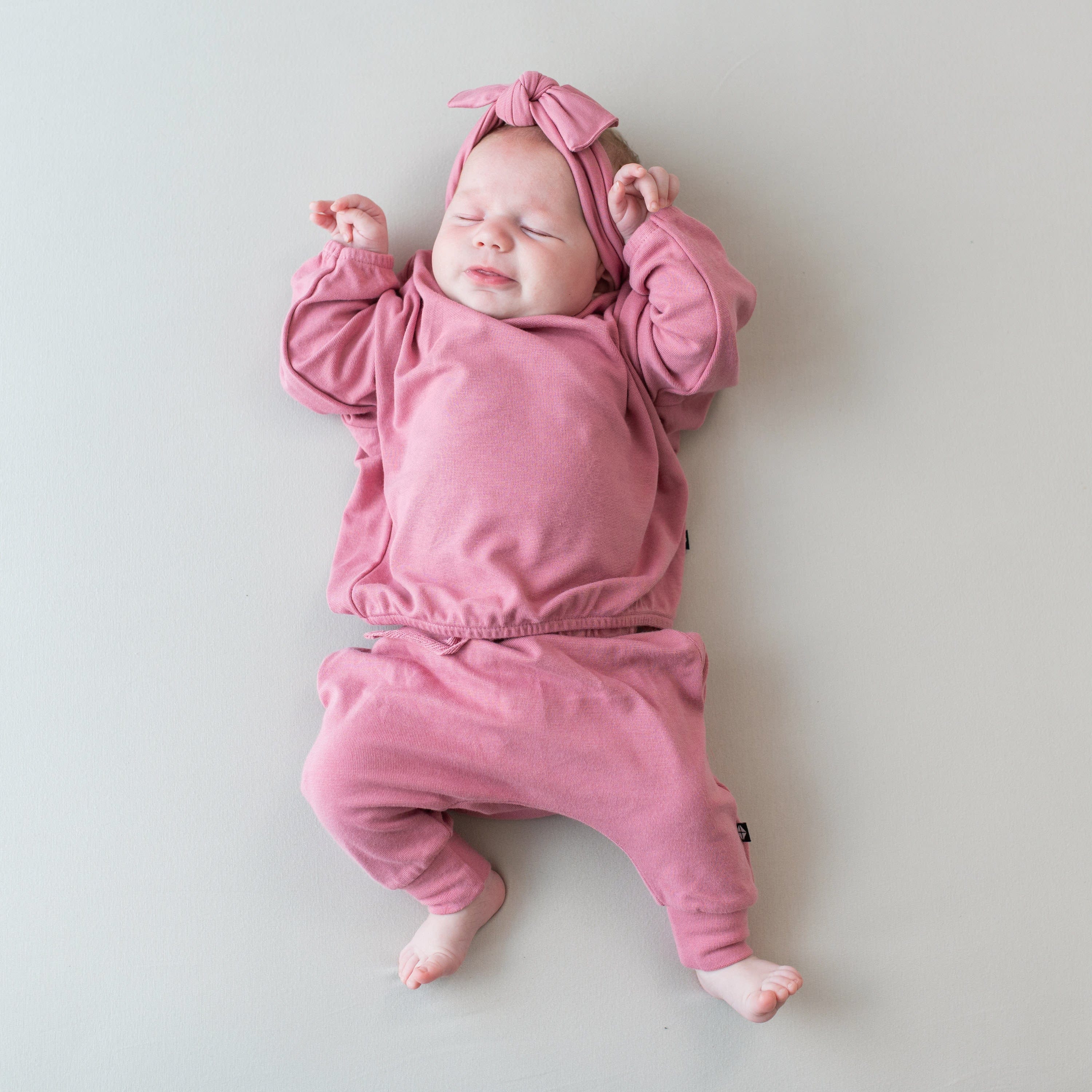 Infant sleeping in Kyte Baby Bamboo Jersey Long Sleeve Drop Shoulder Top in Apple Blossom