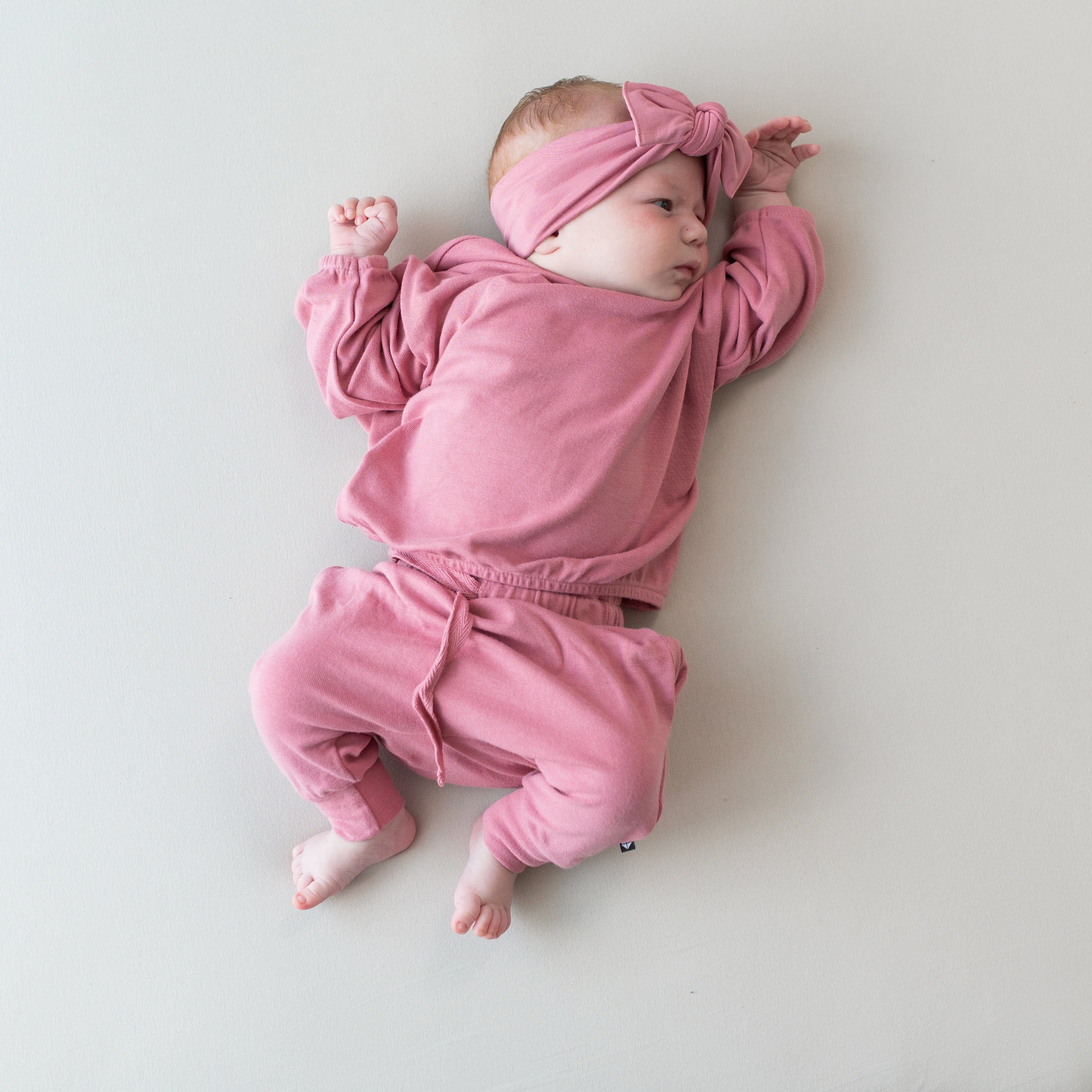 Infant wearing Kyte Baby Bamboo Jersey Drop Shoulder Top with Crew Neck in Apple Blossom