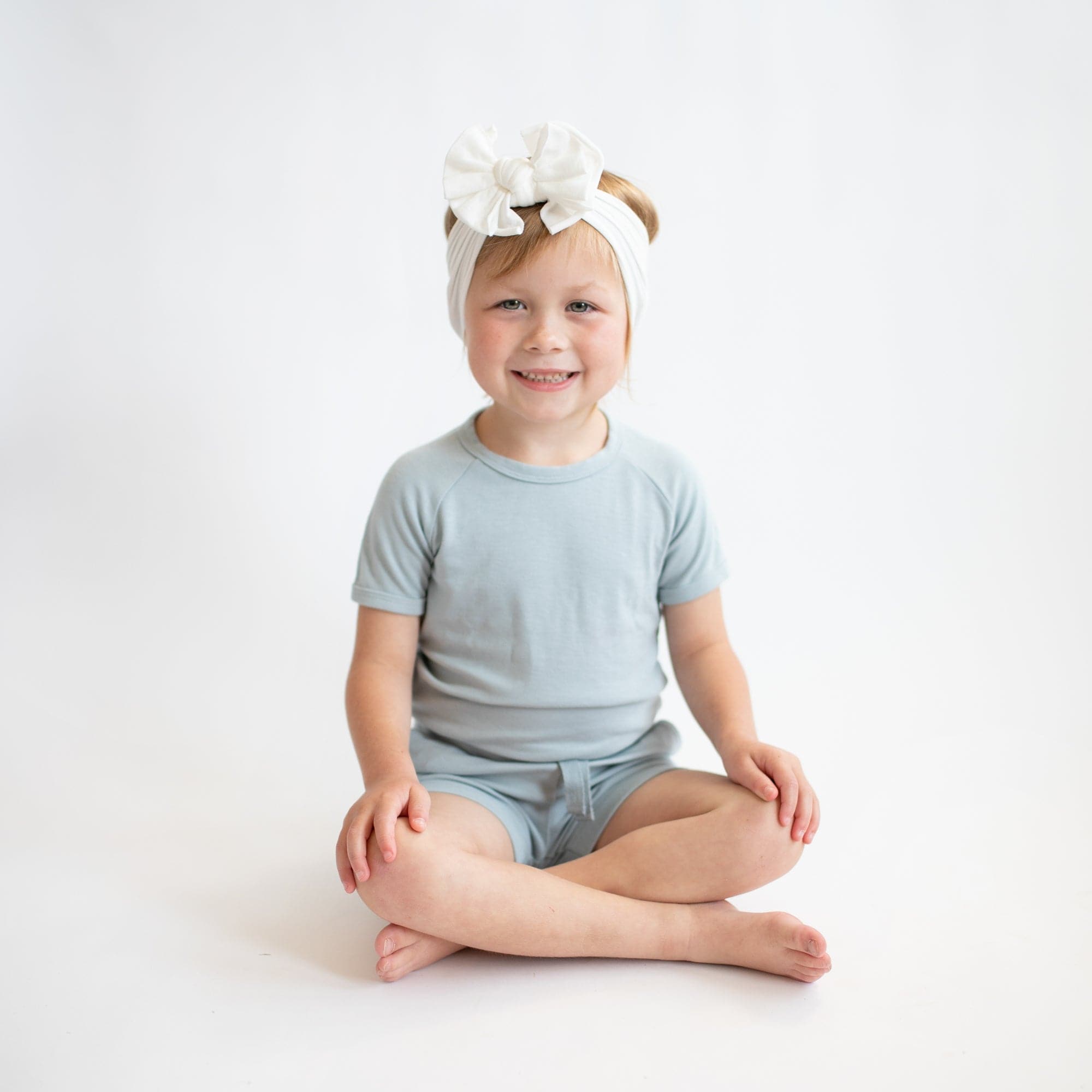 Girl wearing Kyte Baby Bamboo Jersey Short cuffed Sleeve Jogger Set in Fog