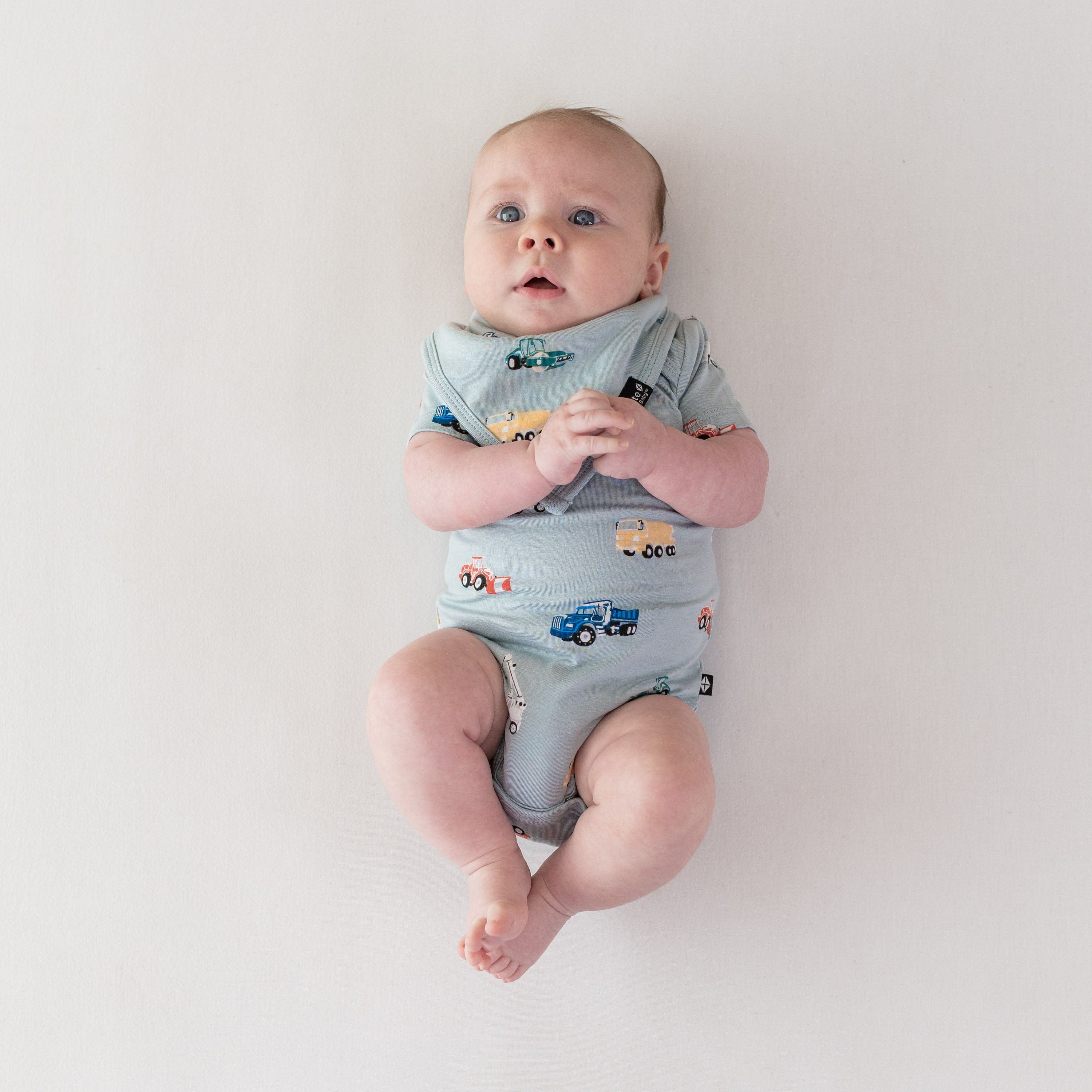 Infant wearing Kyte Baby Bib in Construction and matching bodysuit