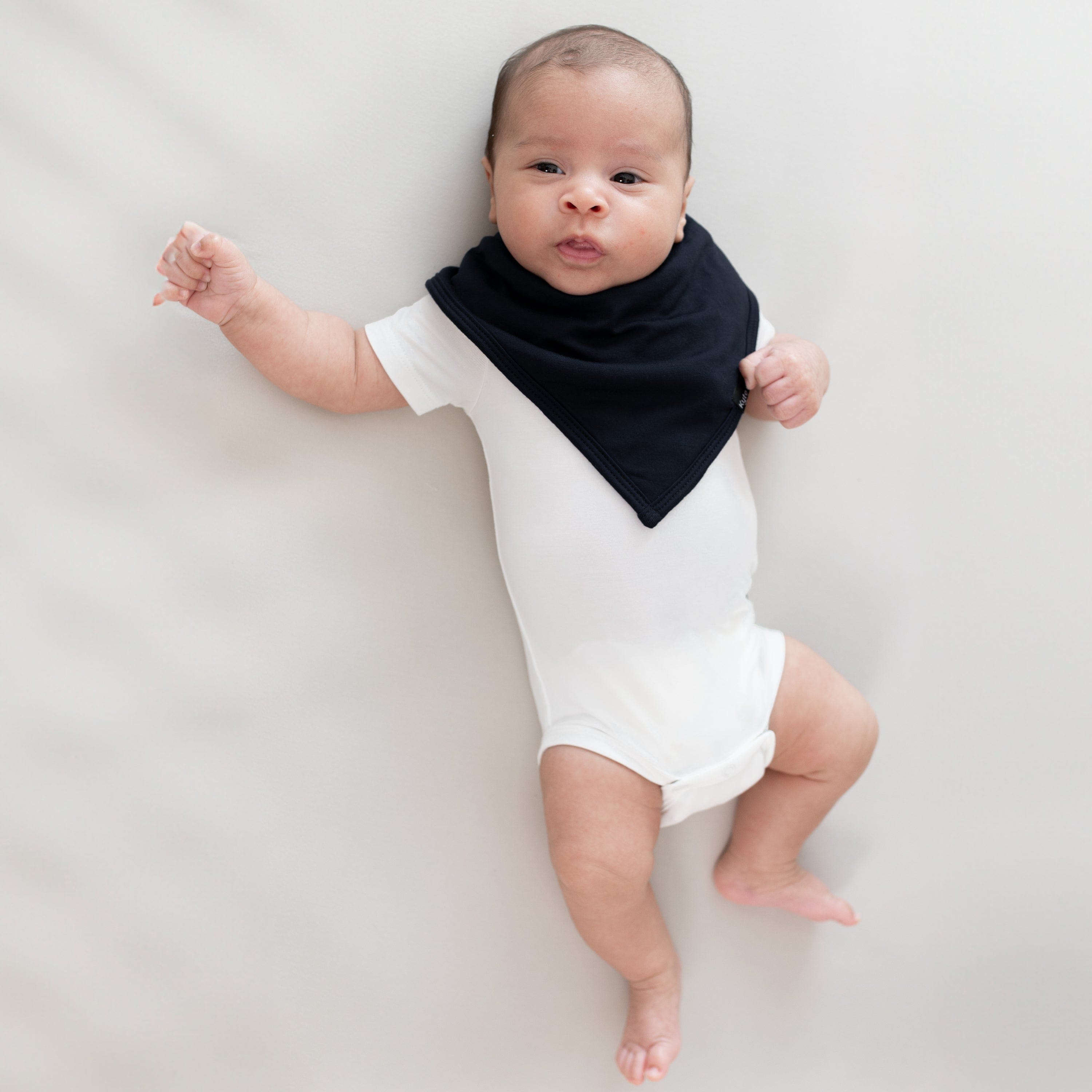Infant laying on its back wearing a Bib in Midnight and Short Sleeve Bodysuit in Cloud