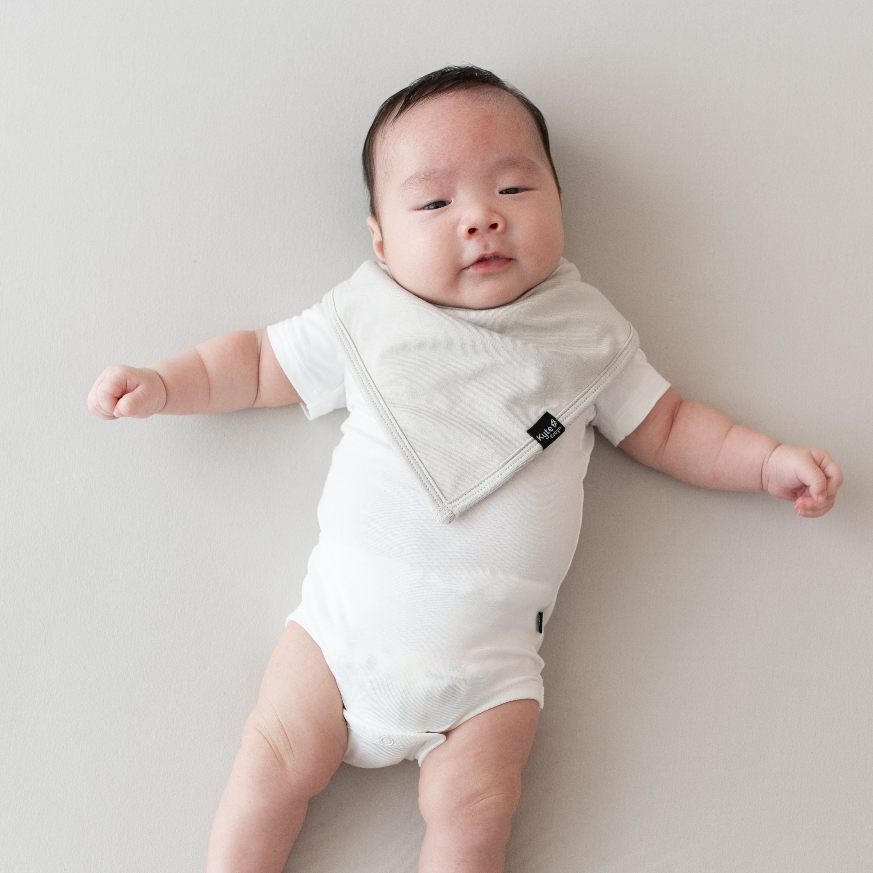 Baby wearing a Bib in Oat and Short Sleeve Bodysuit in Cloud