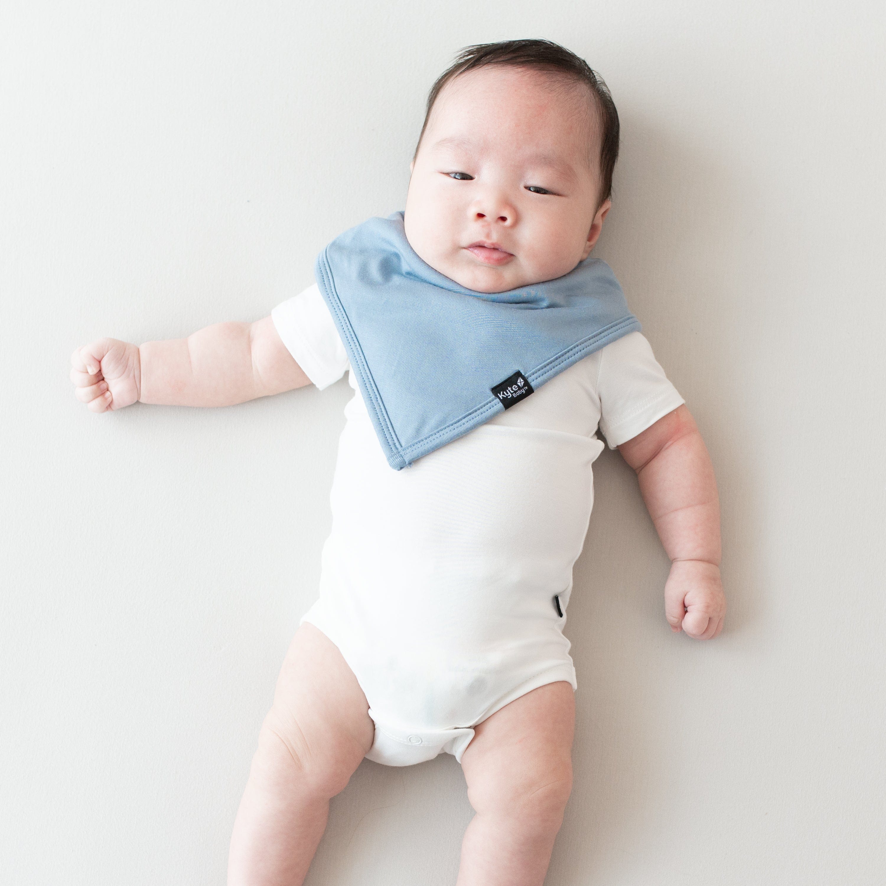 Infant modeling a Kyte Baby Bib in Slate and Short Sleeve Bodysuit in Cloud