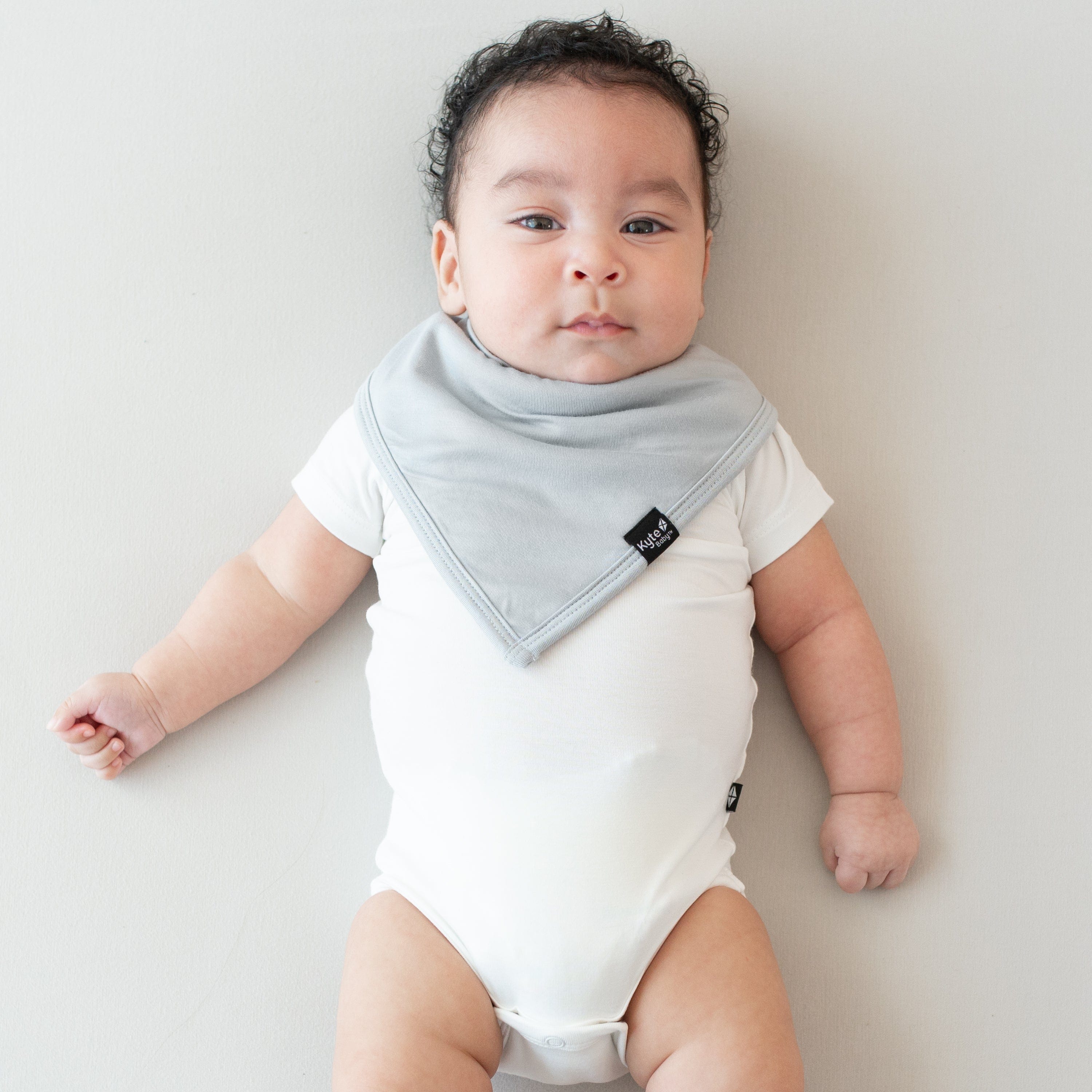 Infant wearing a Kyte Baby Bib in Storm and Short Sleeve Bodysuit in Cloud