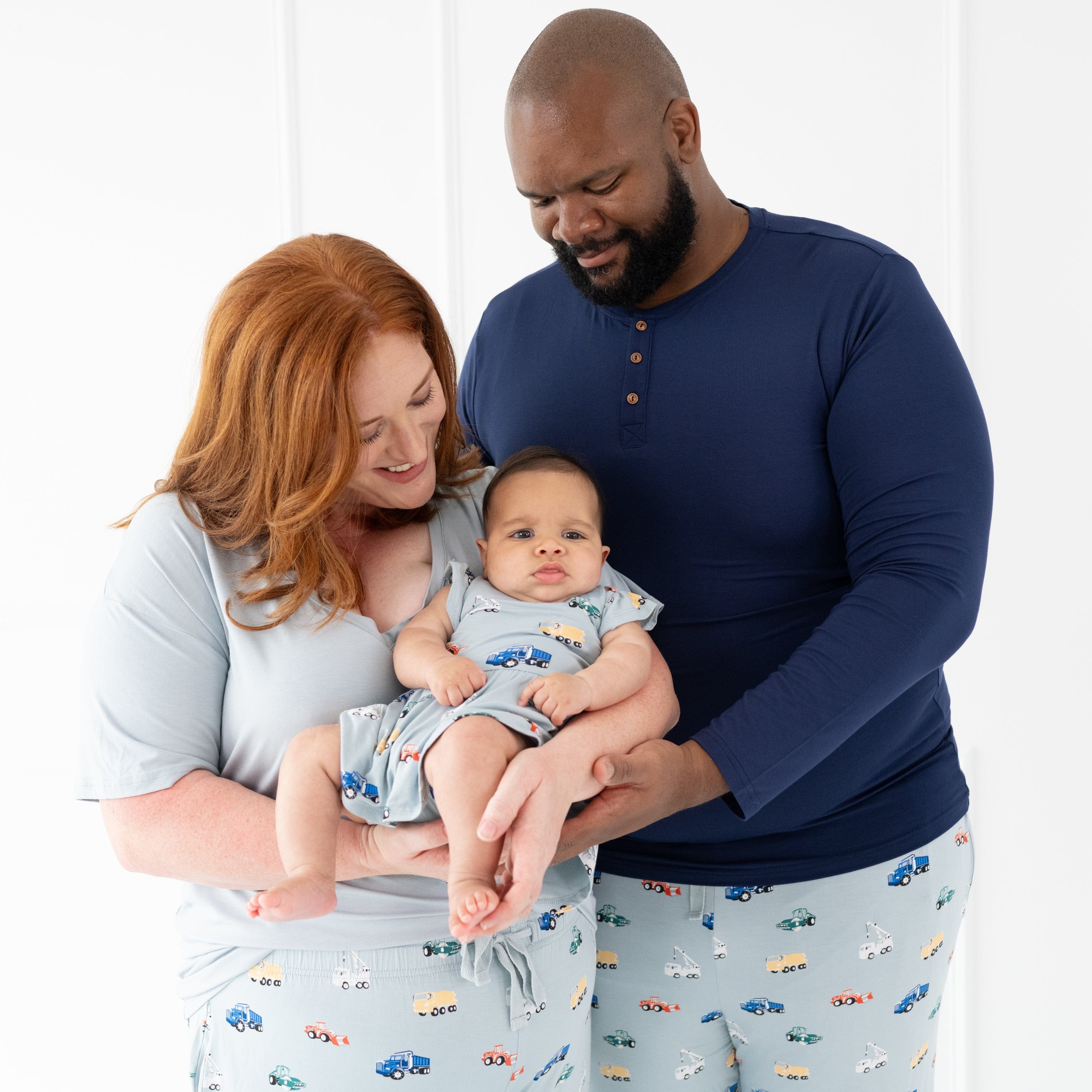 Mom, Dad, and Daughter wearing matching family outfits in Construction print