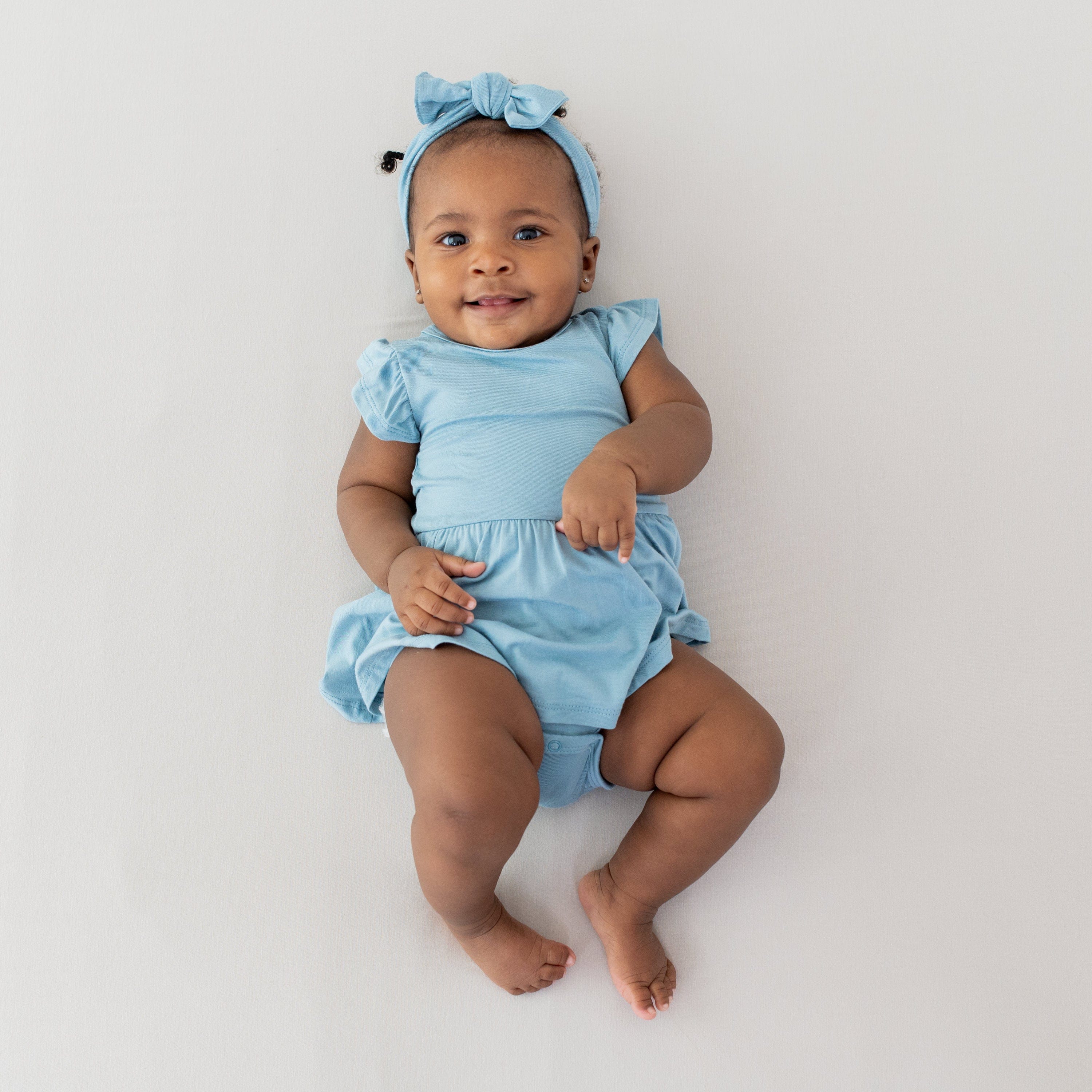Infant wearing Kyte Baby Twirl Bodysuit in Dusty Blue