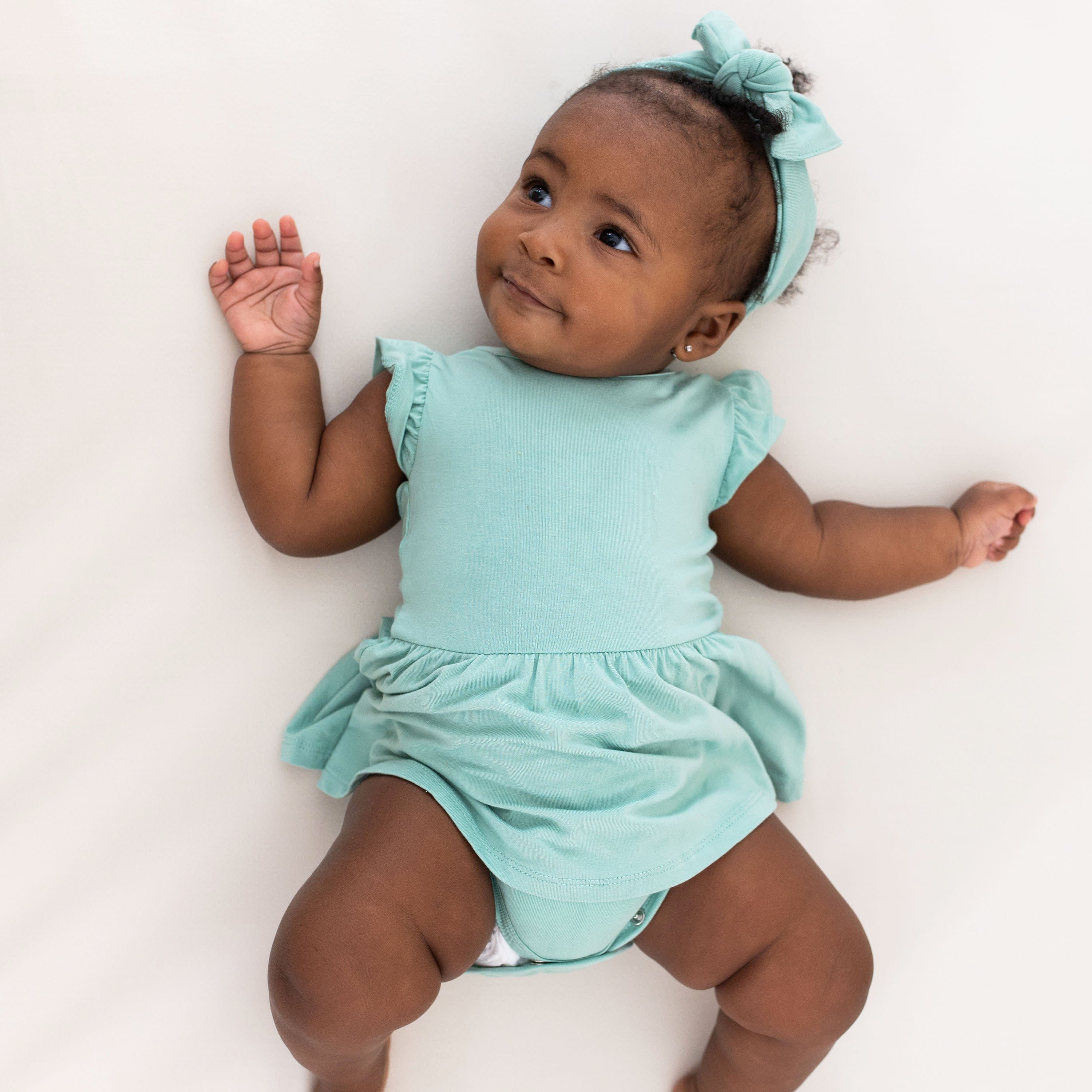 Baby wearing Kyte Baby Bodysuit with Twirl Skirt in Wasabi