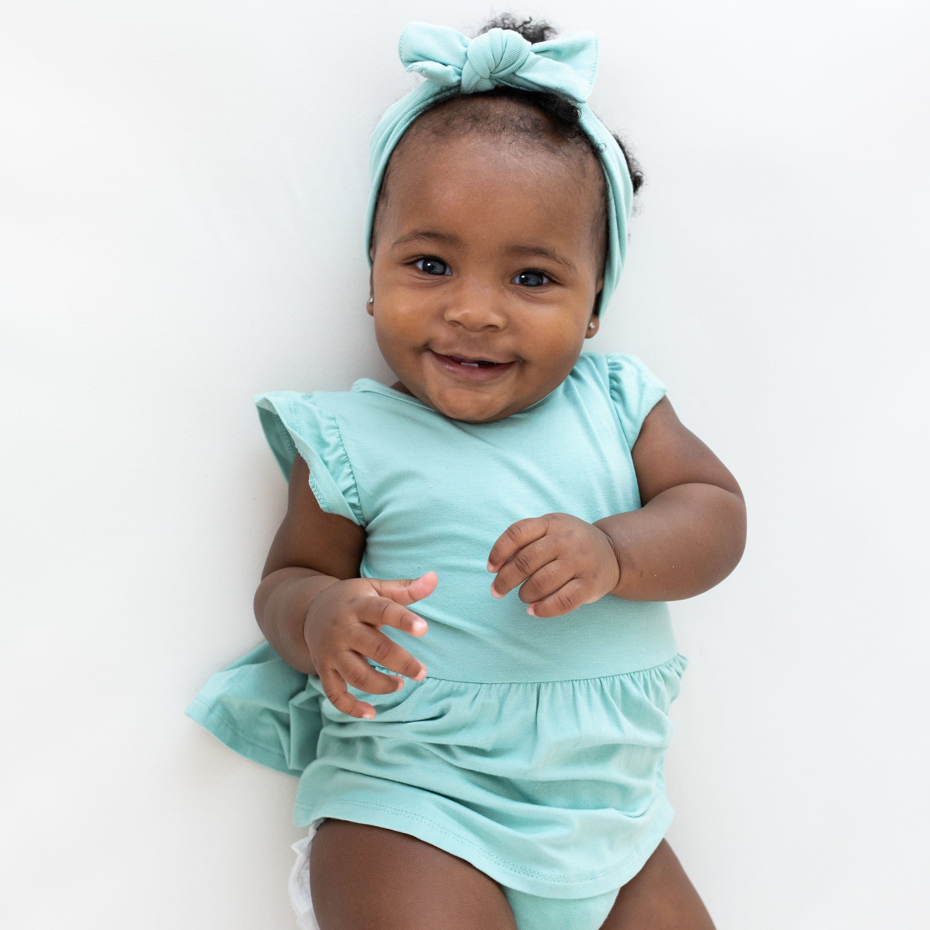 Infant wearing Kyte Baby Twirl Bodysuit in Wasabi