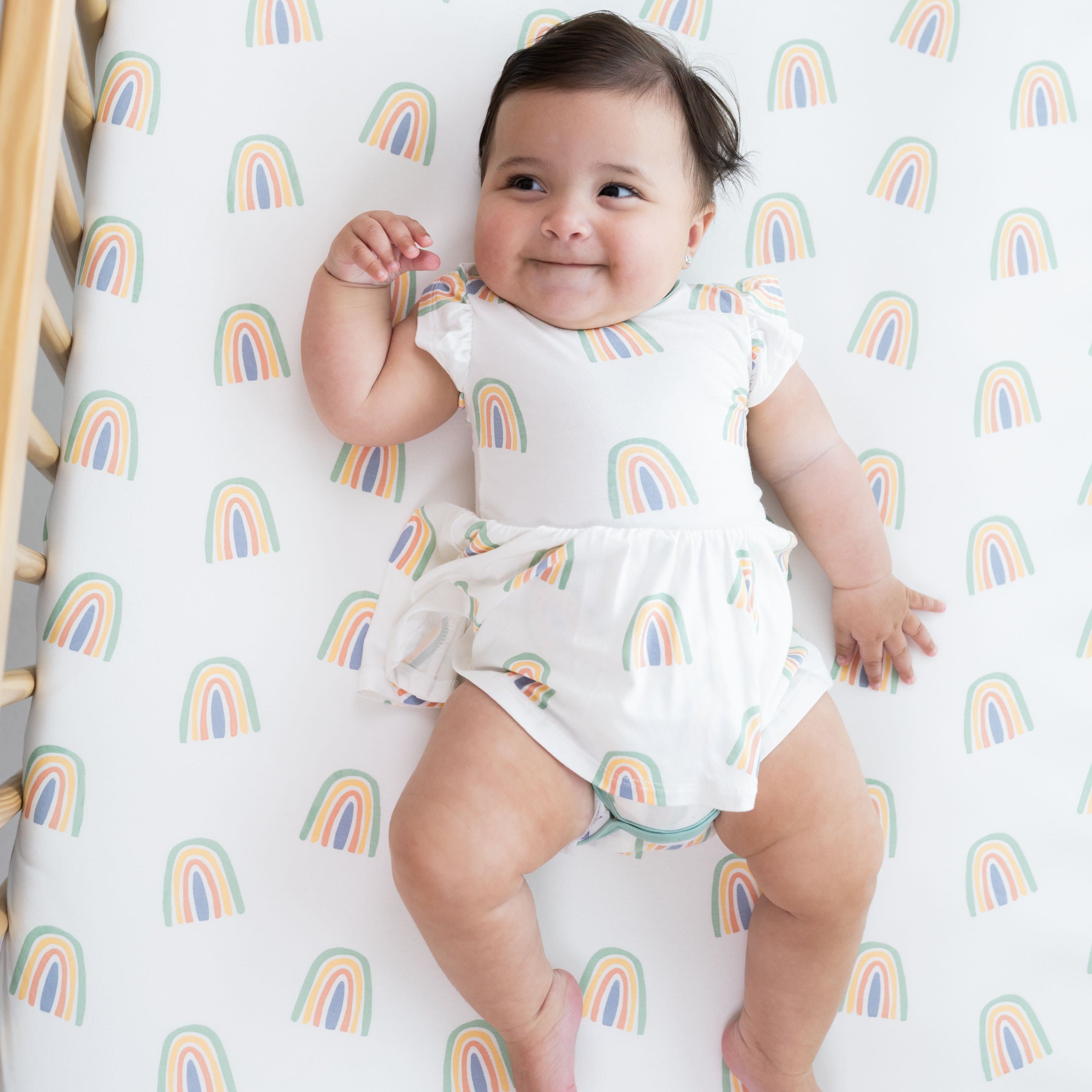 Infant wearing Kyte Baby Twirl Bodysuit in Wasabi Rainbow